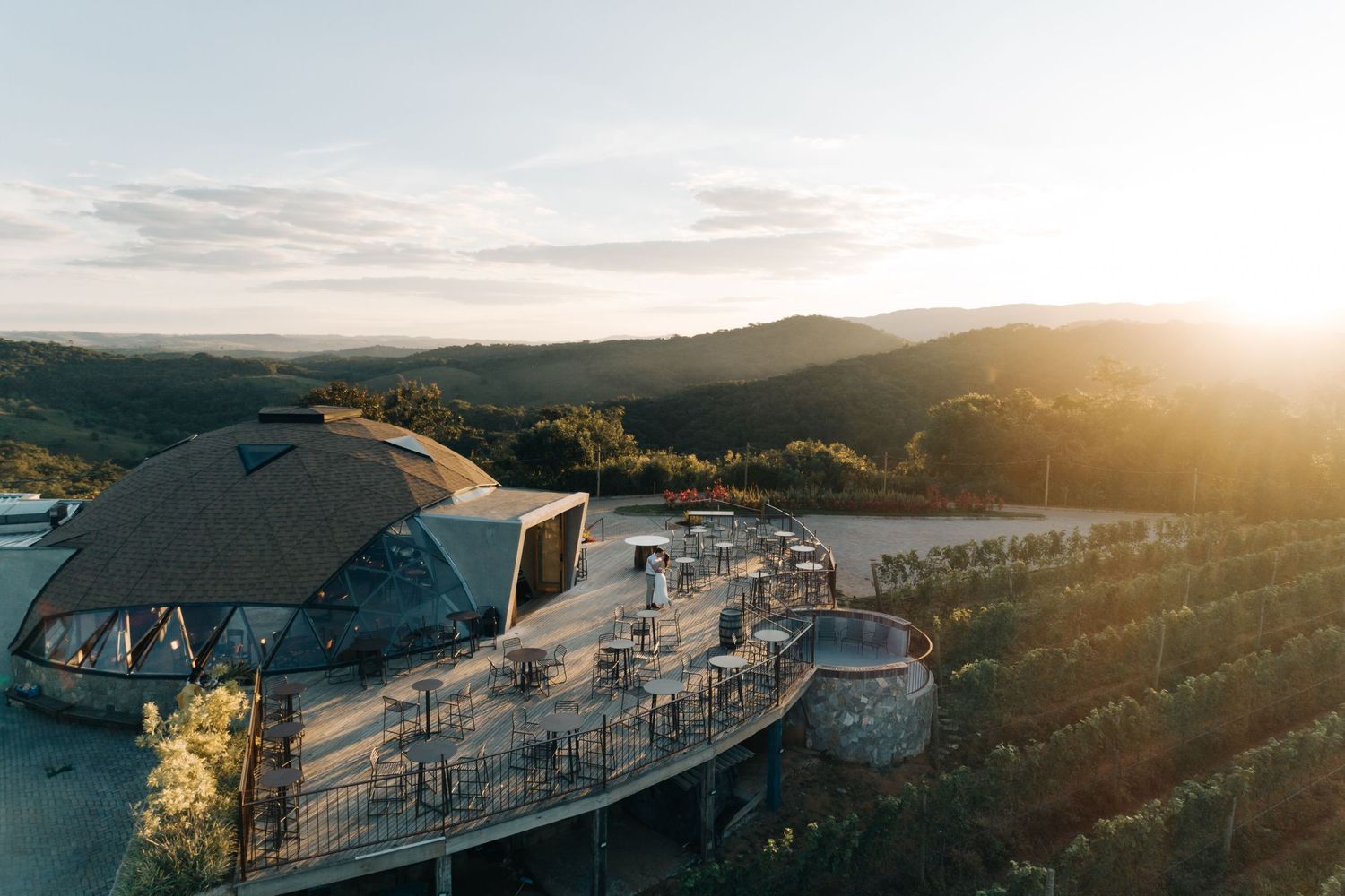 Luxury resort with curved architecture perched on a hilltop overlooks mountains during golden sunset hour.