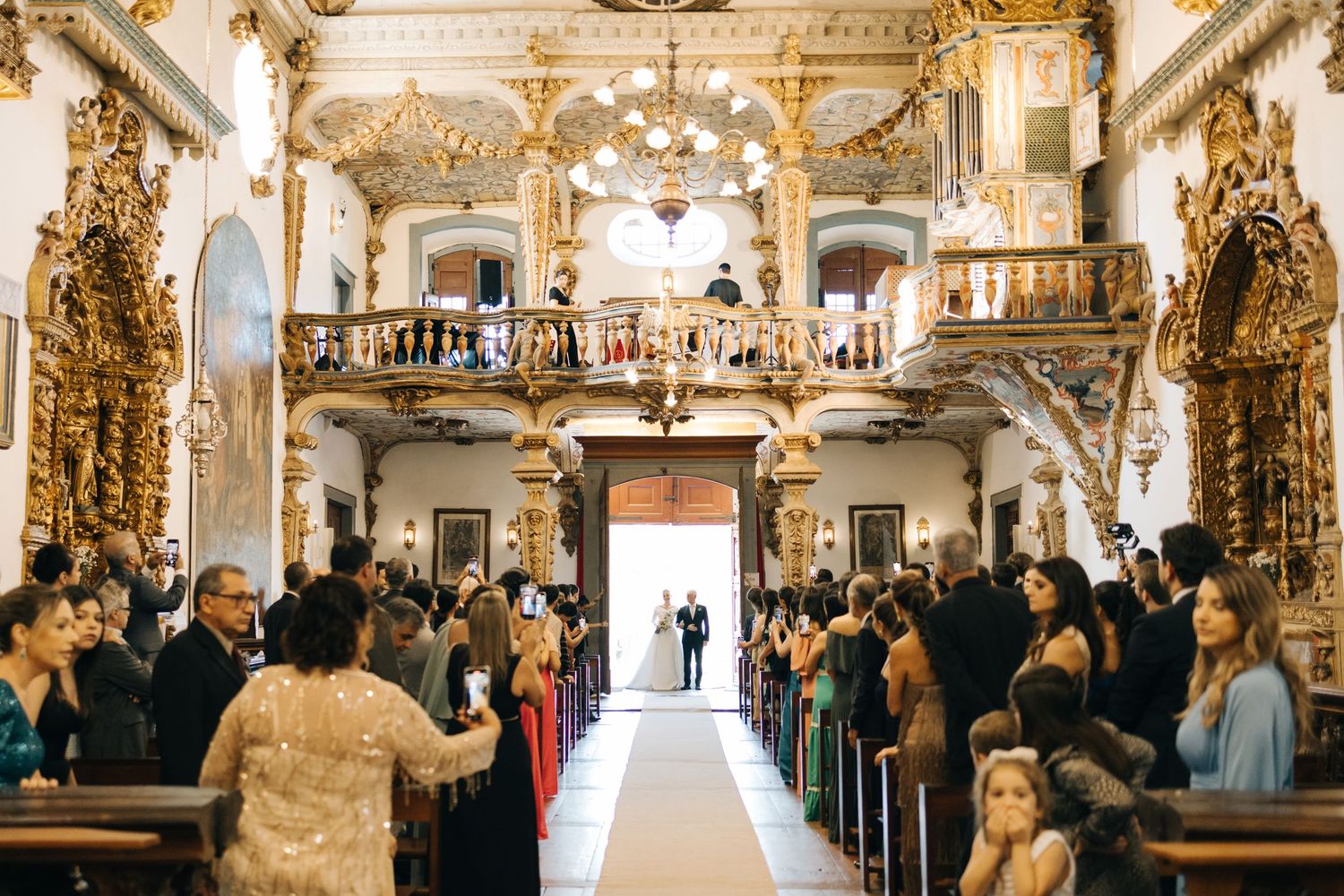 Grand baroque church interior filled with wedding guests and golden architectural details.
