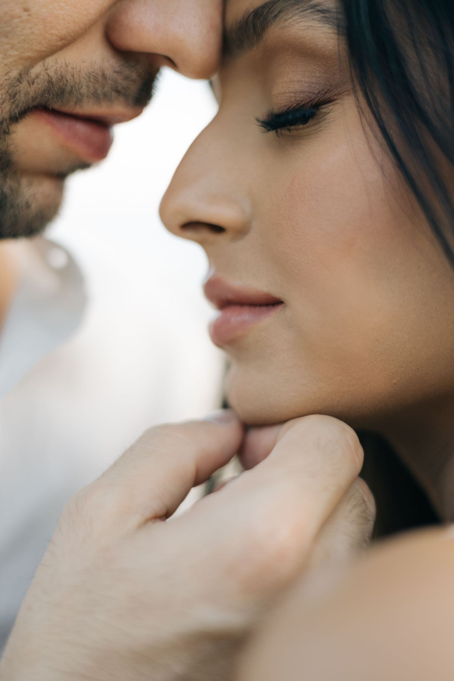 Intimate close-up portrait of couple in tender romantic moment with soft lighting.