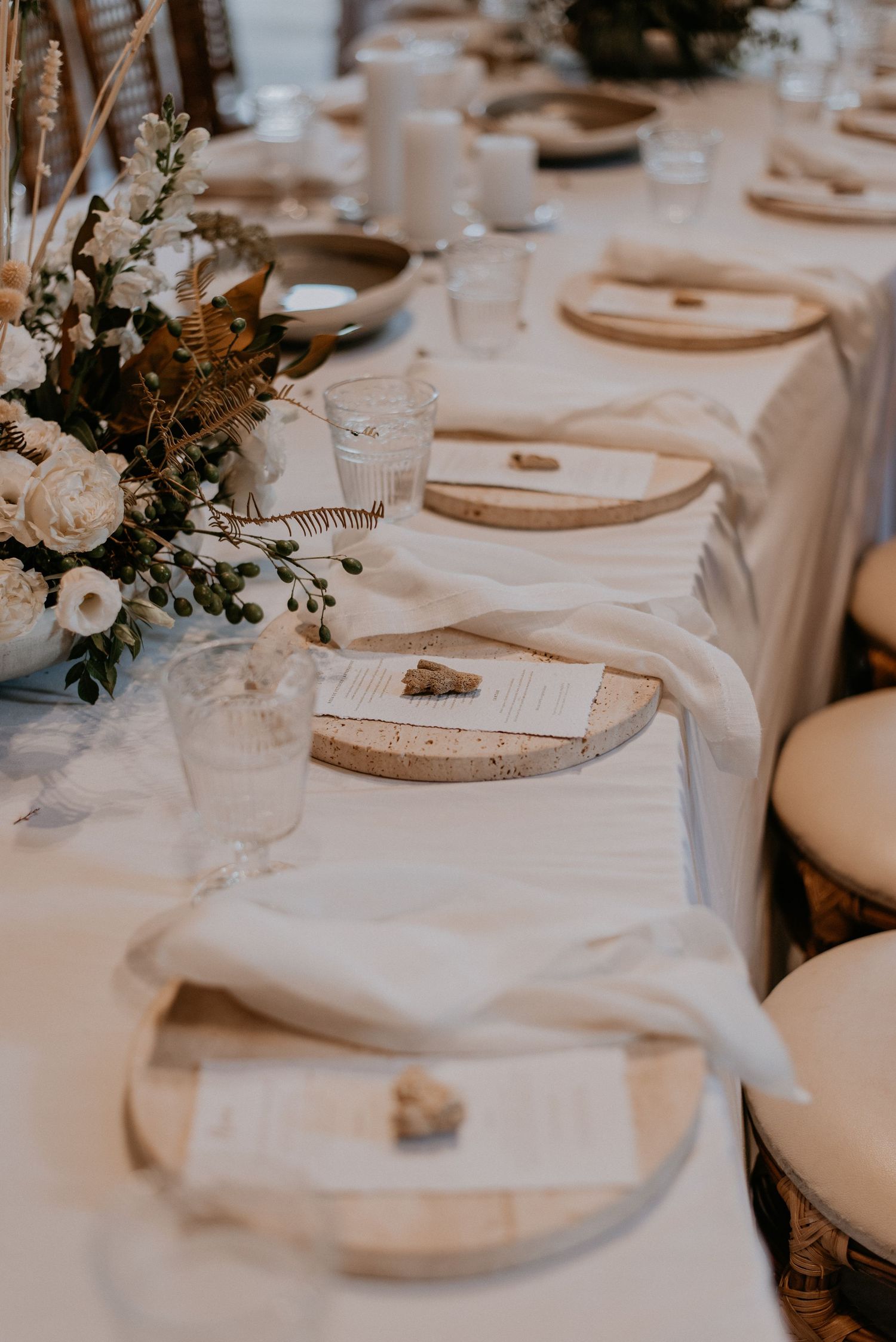 Close-up of elegant wedding table settings with white flowers and cork place card holders.