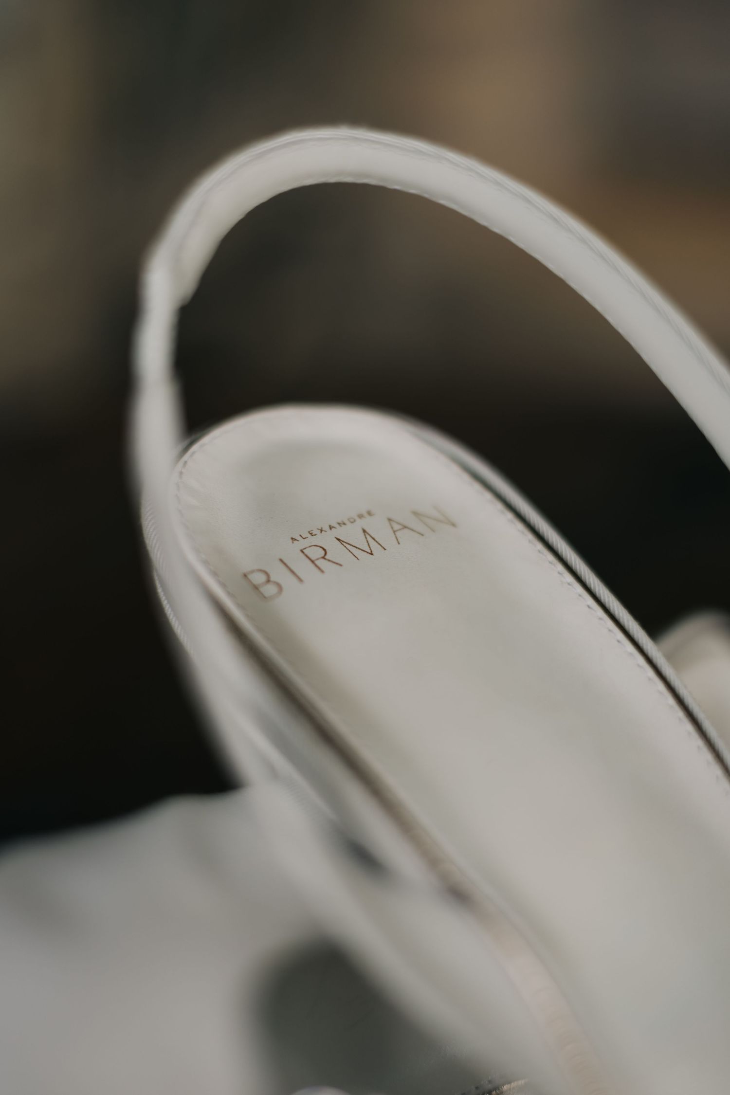 Close-up detail of a white Birman brand shoe label on an elegant slingback heel.