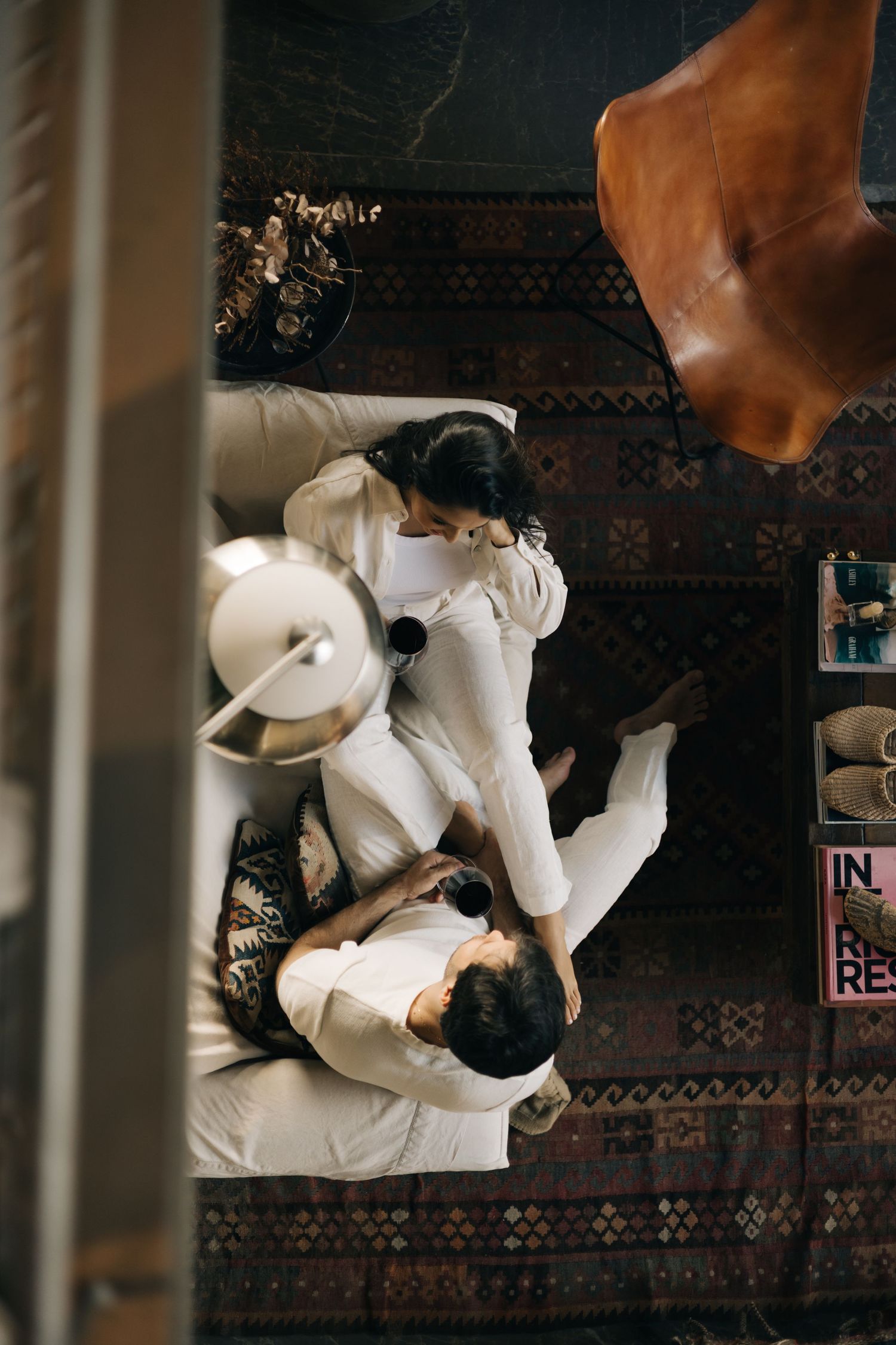 Two dogs cuddling and playing together on a patterned brown rug seen from above.