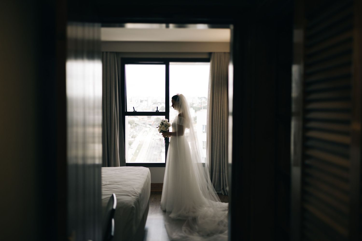Silhouette wedding photo through a doorway showing a figure by a window.