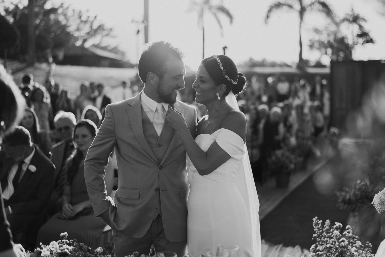 Black and white portrait of newlyweds sharing intimate moment at outdoor reception.