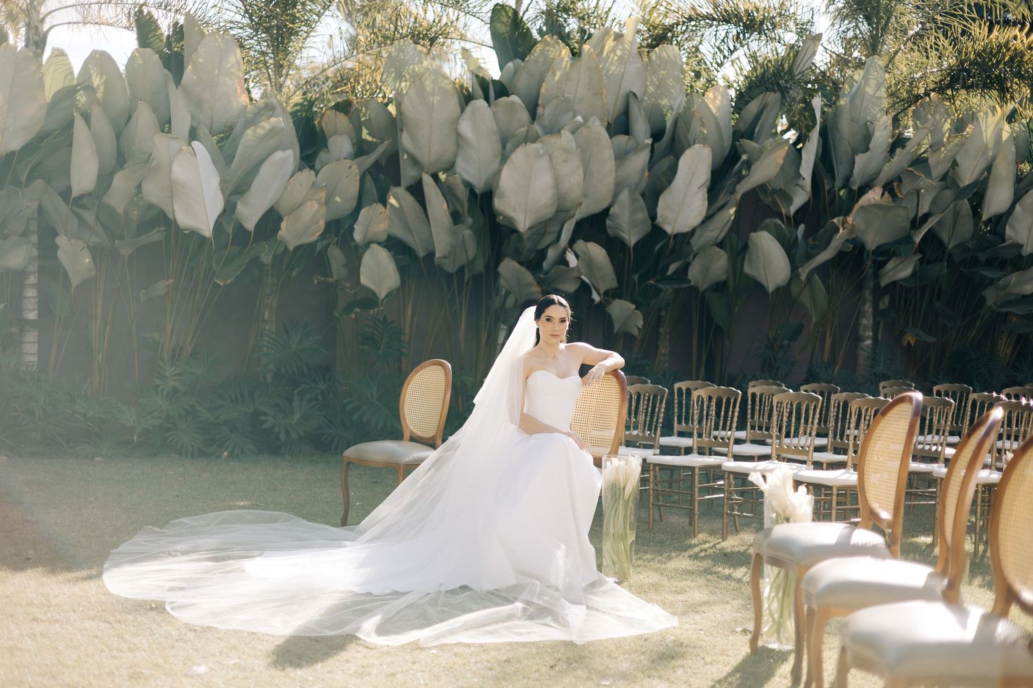 White gowns and formal attire adorn guests and participants at an outdoor garden wedding ceremony and reception.