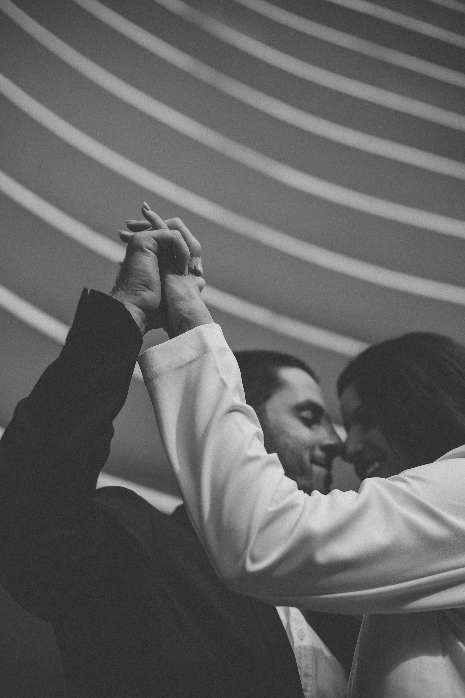 A black and white photo of two figures holding hands, with diagonal lines visible in the background.