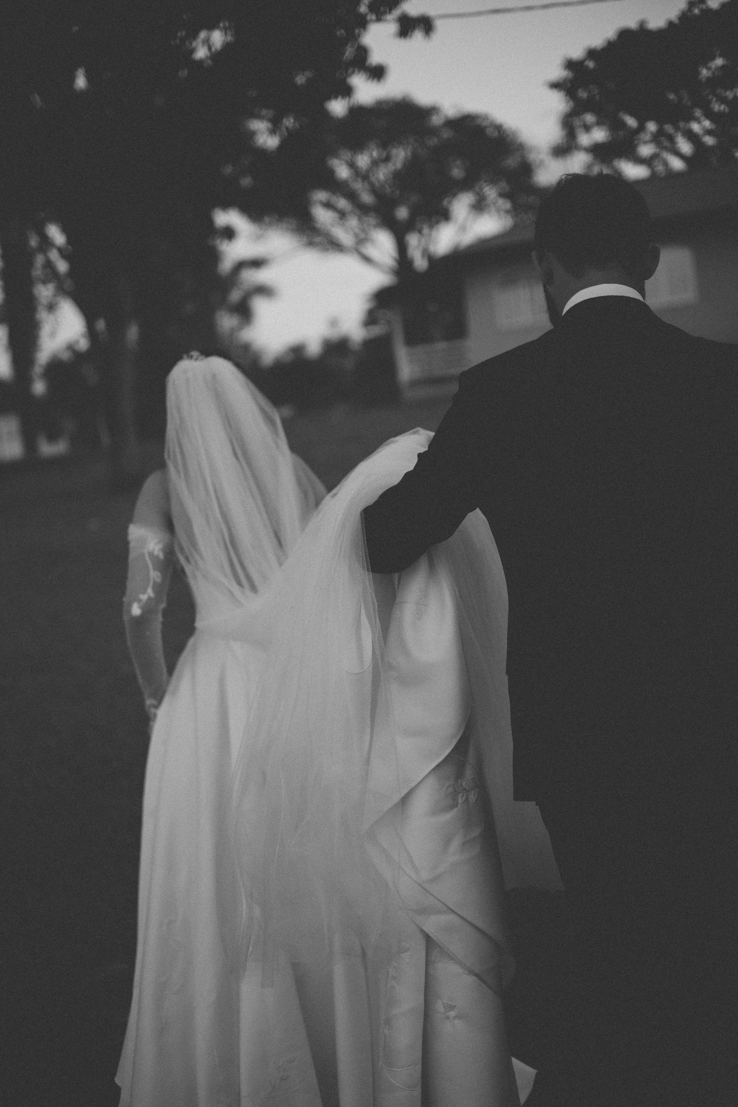 Black and white photo of a bride and groom embracing outside on their wedding day.