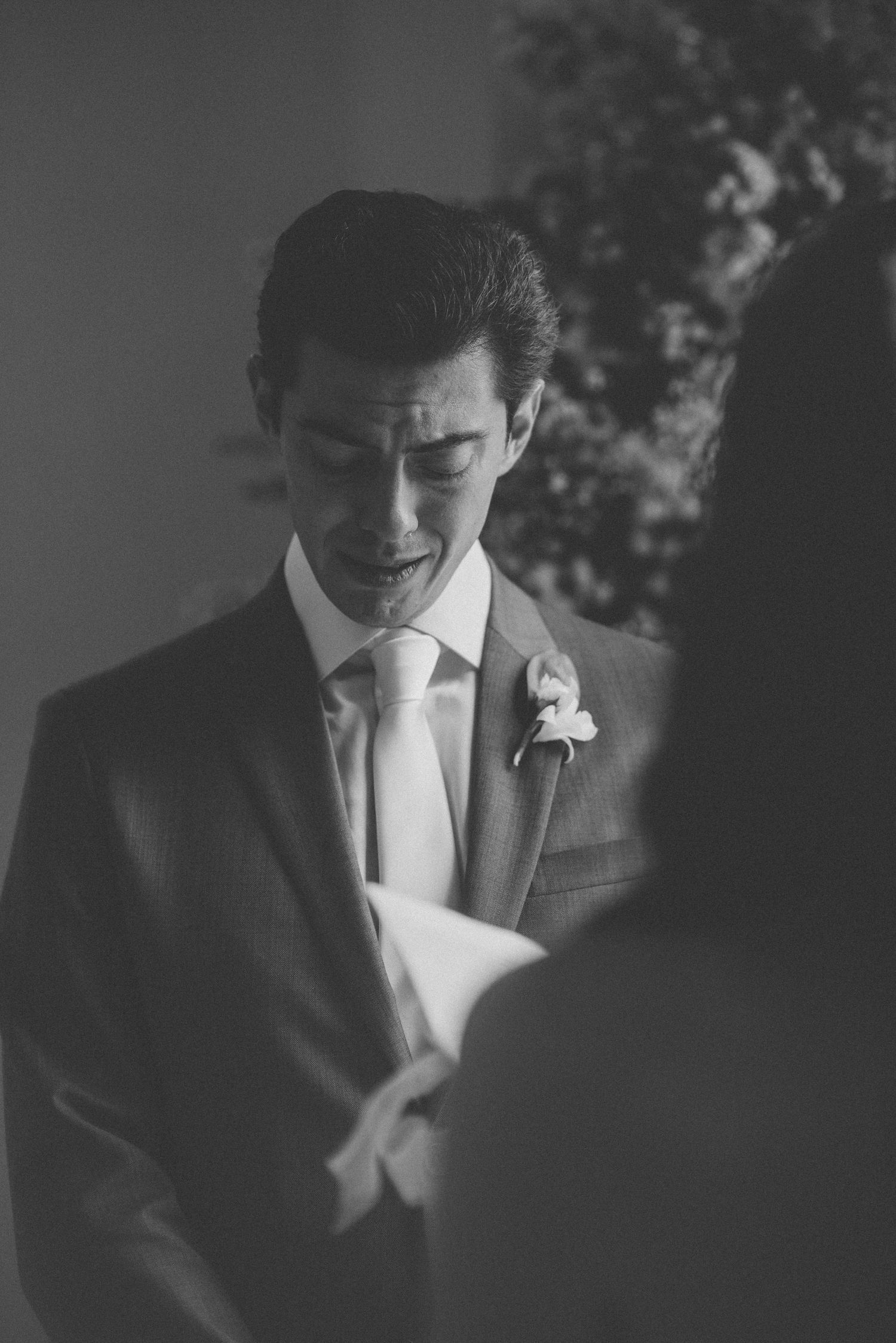 A black and white portrait of a suited groom with a boutonniere.
