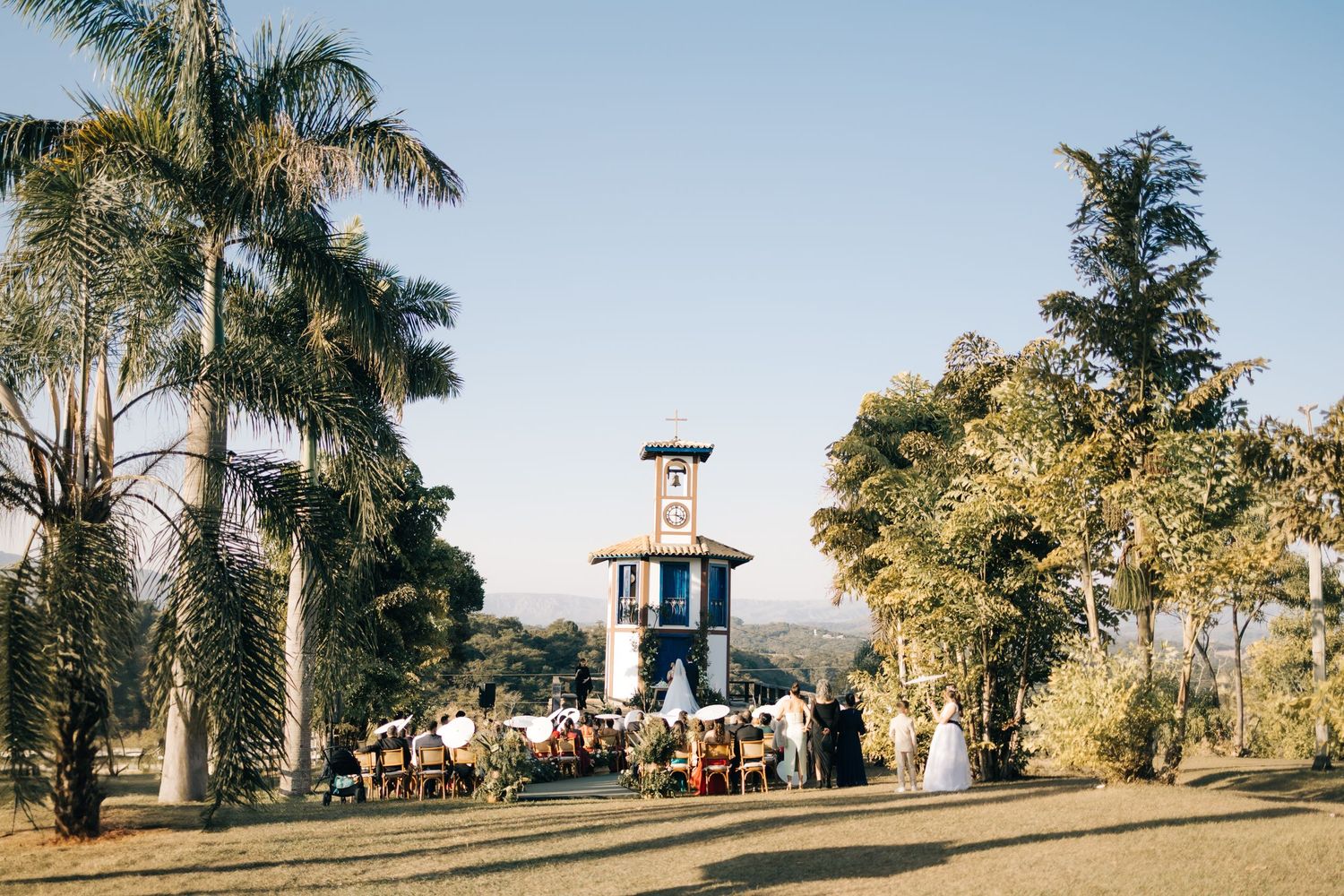Scenic view of a gazebo structure surrounded by palm trees and visitors at a hilltop observation point.