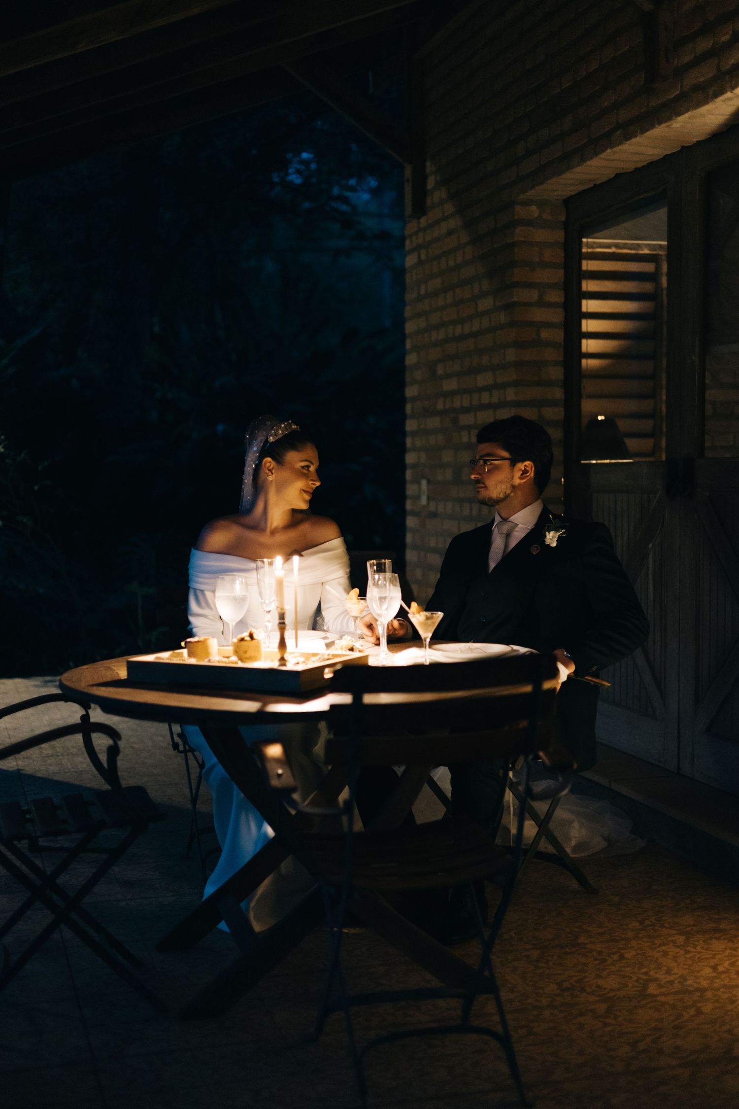 A couple shares an intimate candlelit dinner on their wedding night.