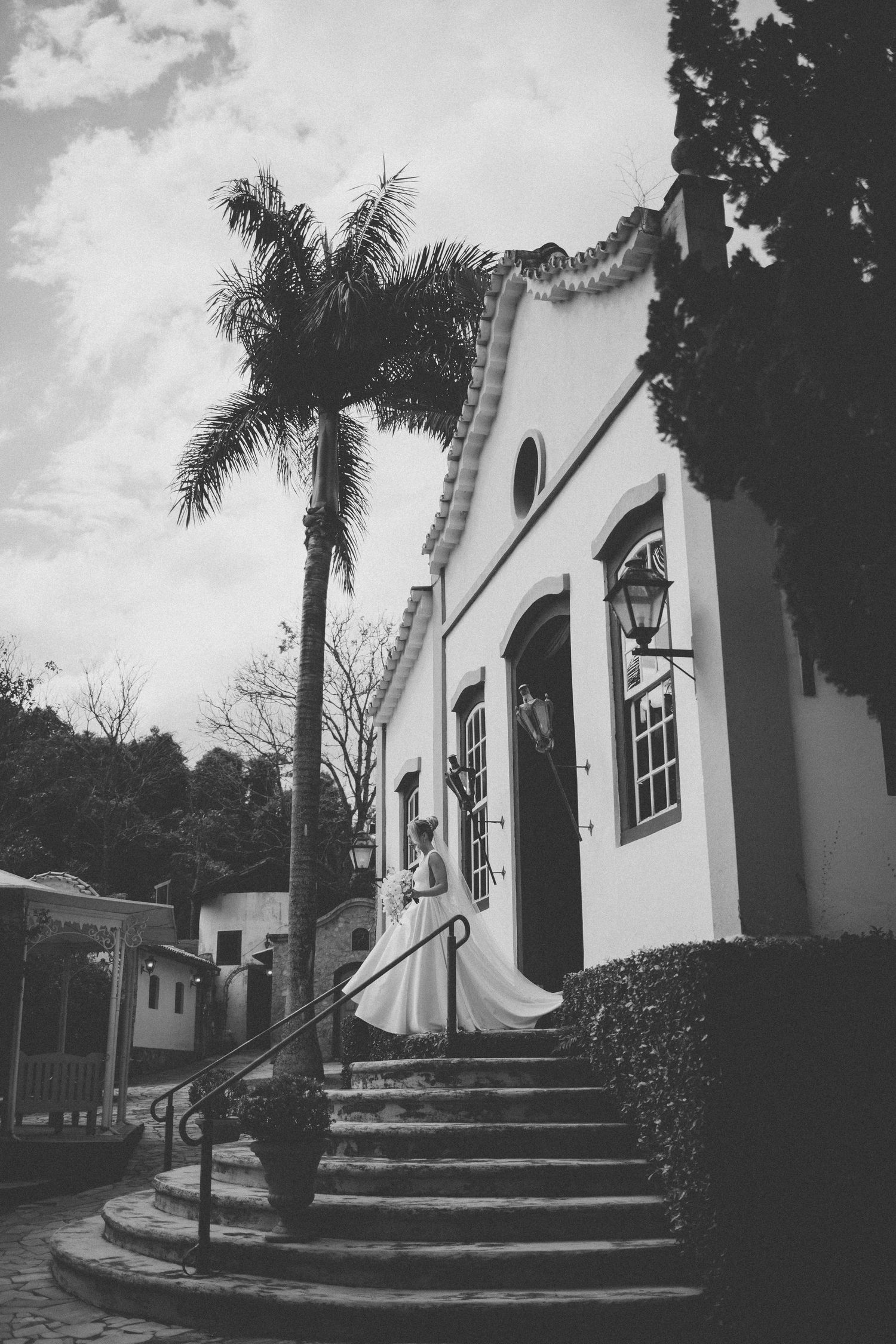Black and white photo of a historic Spanish colonial church with palm trees and curved stone steps leading to entrance.