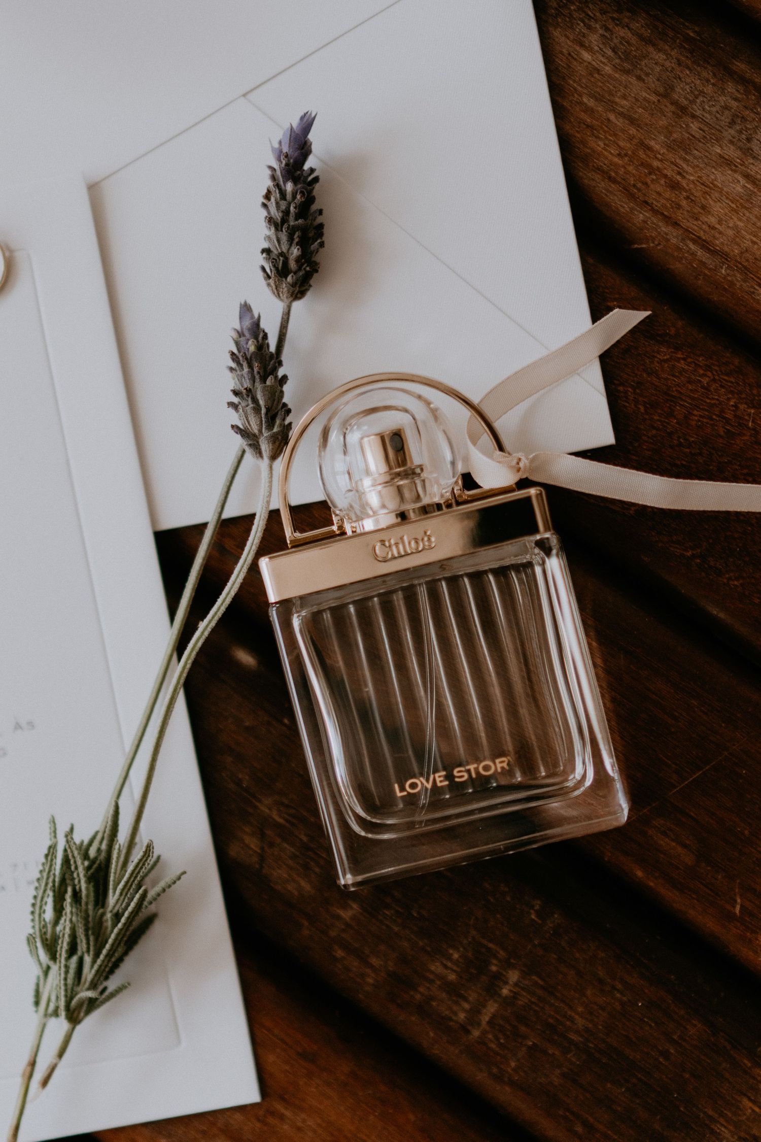 Elegant perfume bottle with lavender sprigs styled on wooden surface.