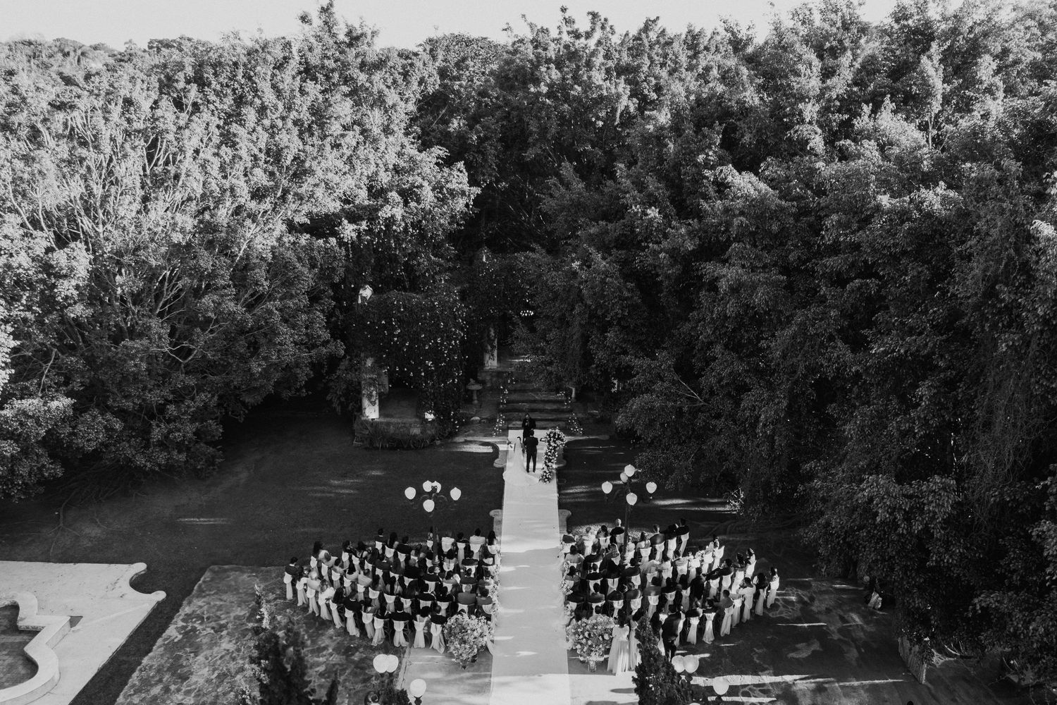 Bird's eye view of wedding ceremony seating arranged symmetrically in a garden setting.