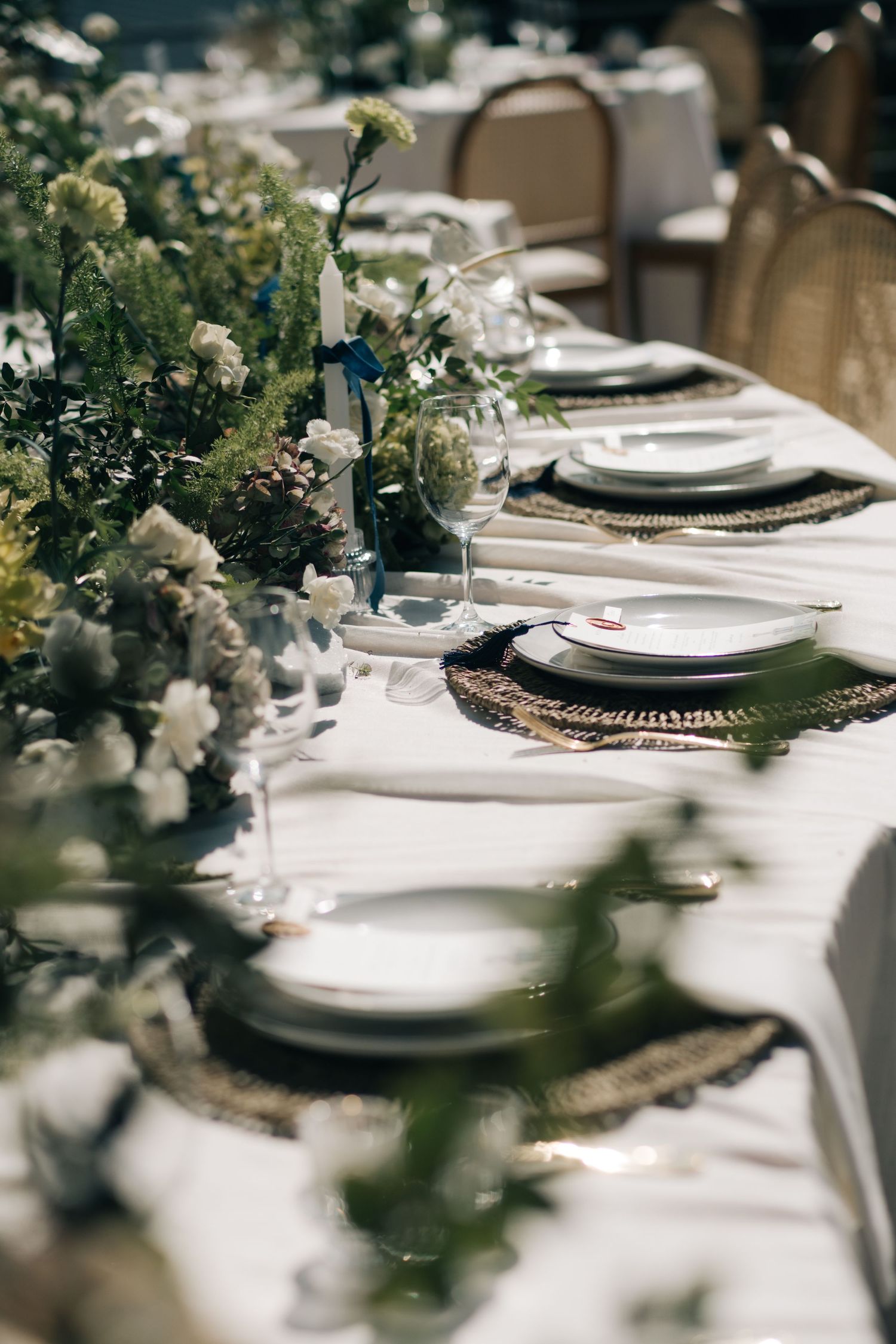 Elegant wedding table setting with delicate white floral arrangements and vintage charger plates on crisp white linens.