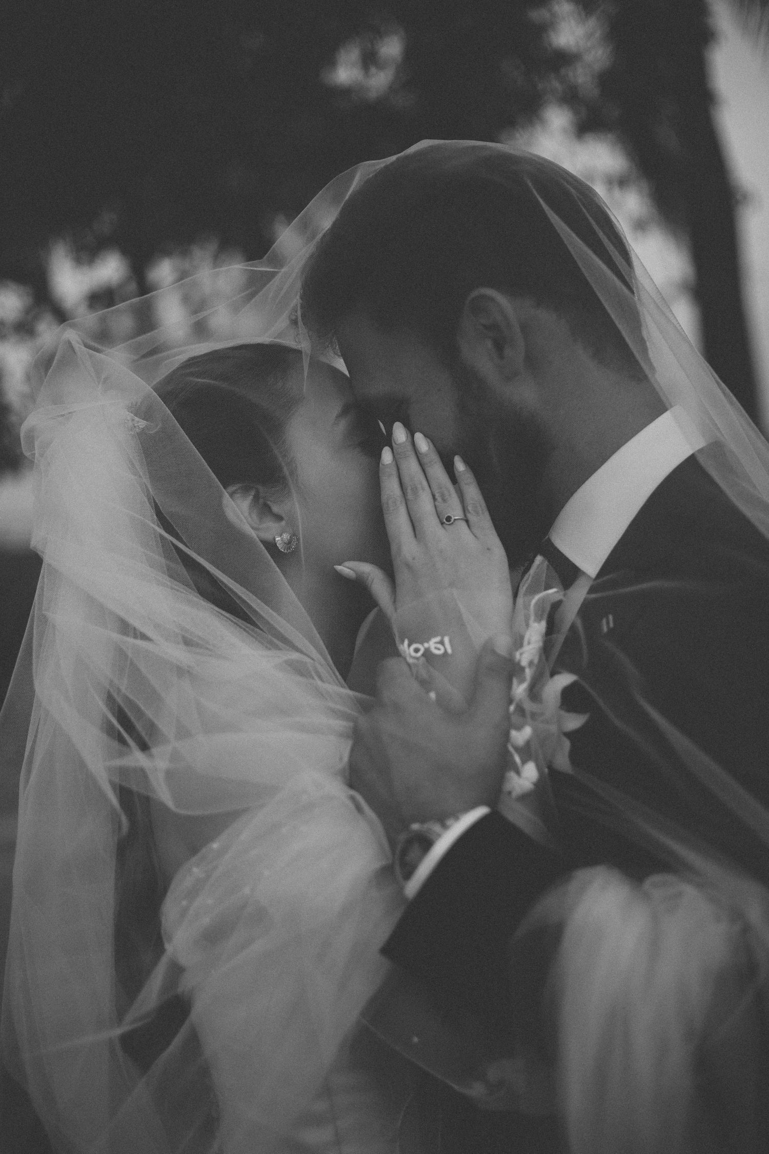 Intimate black and white wedding portrait showing tender moment between newlyweds.