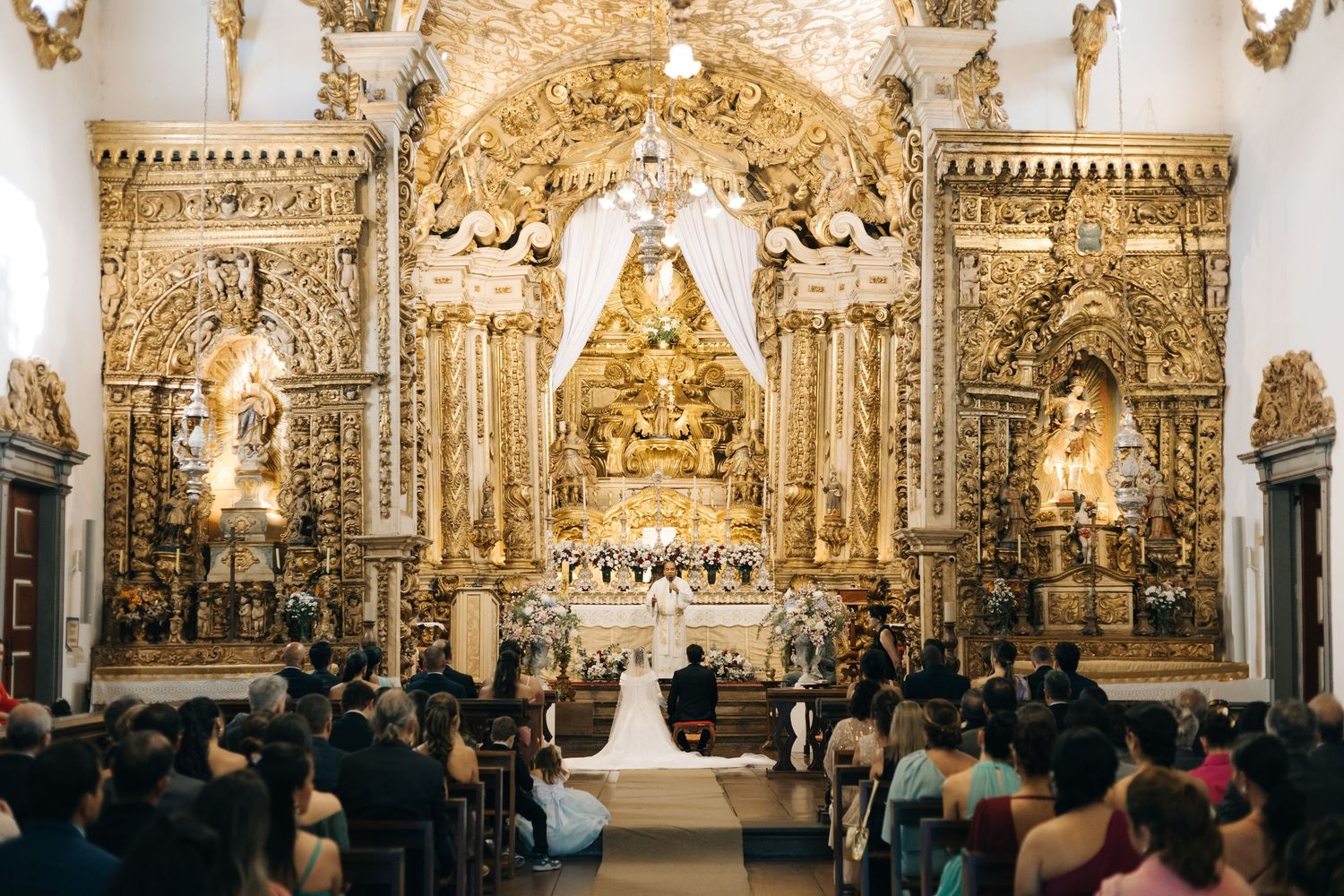 Elaborate baroque church altar glowing in golden light during wedding ceremony.