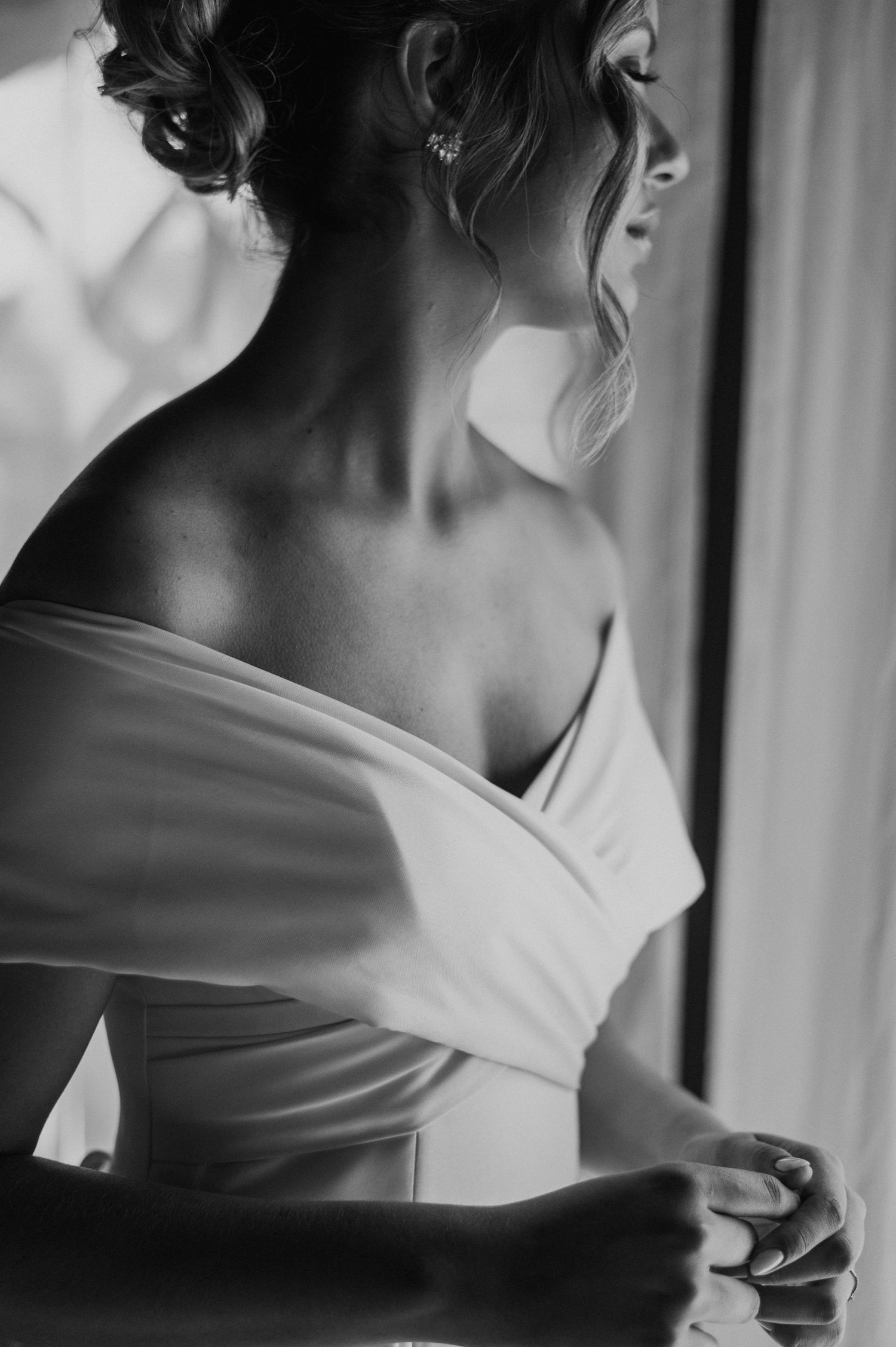 Artistic black and white shot of an elegant off-shoulder wedding dress detail.
