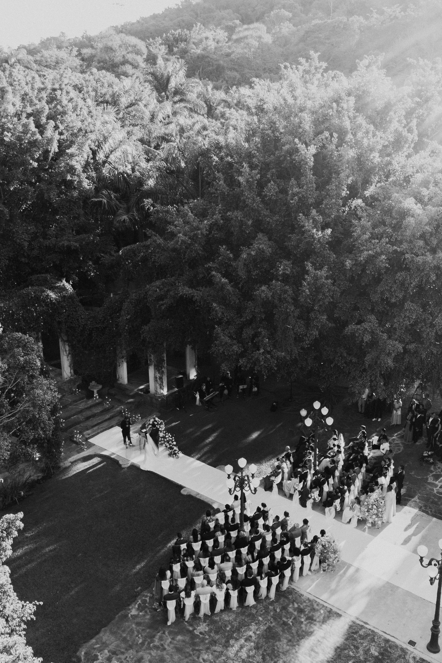 Aerial view of wedding guests arranged in rows during an outdoor garden ceremony.