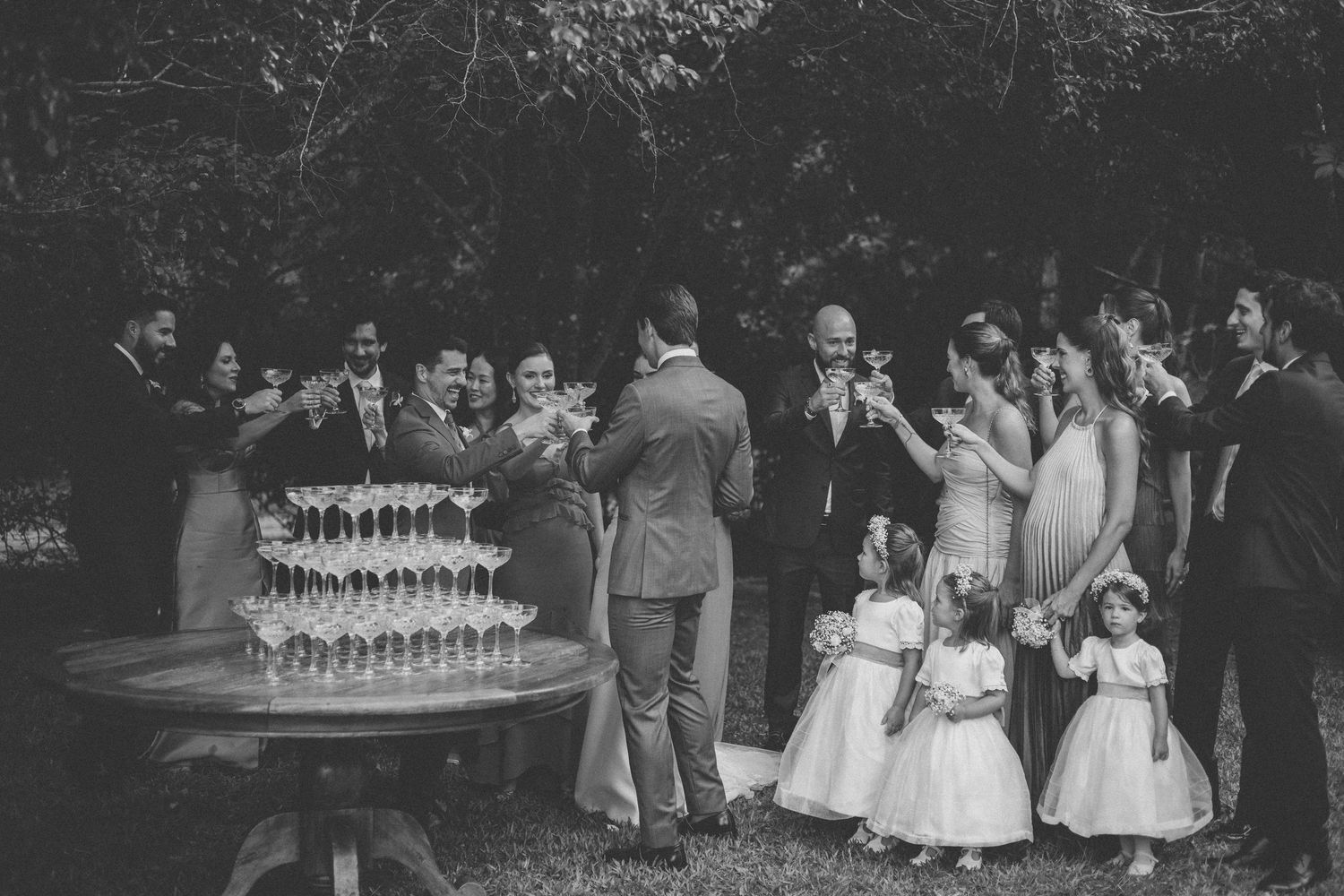 Black and white photo of wedding guests gathering around a champagne tower display.