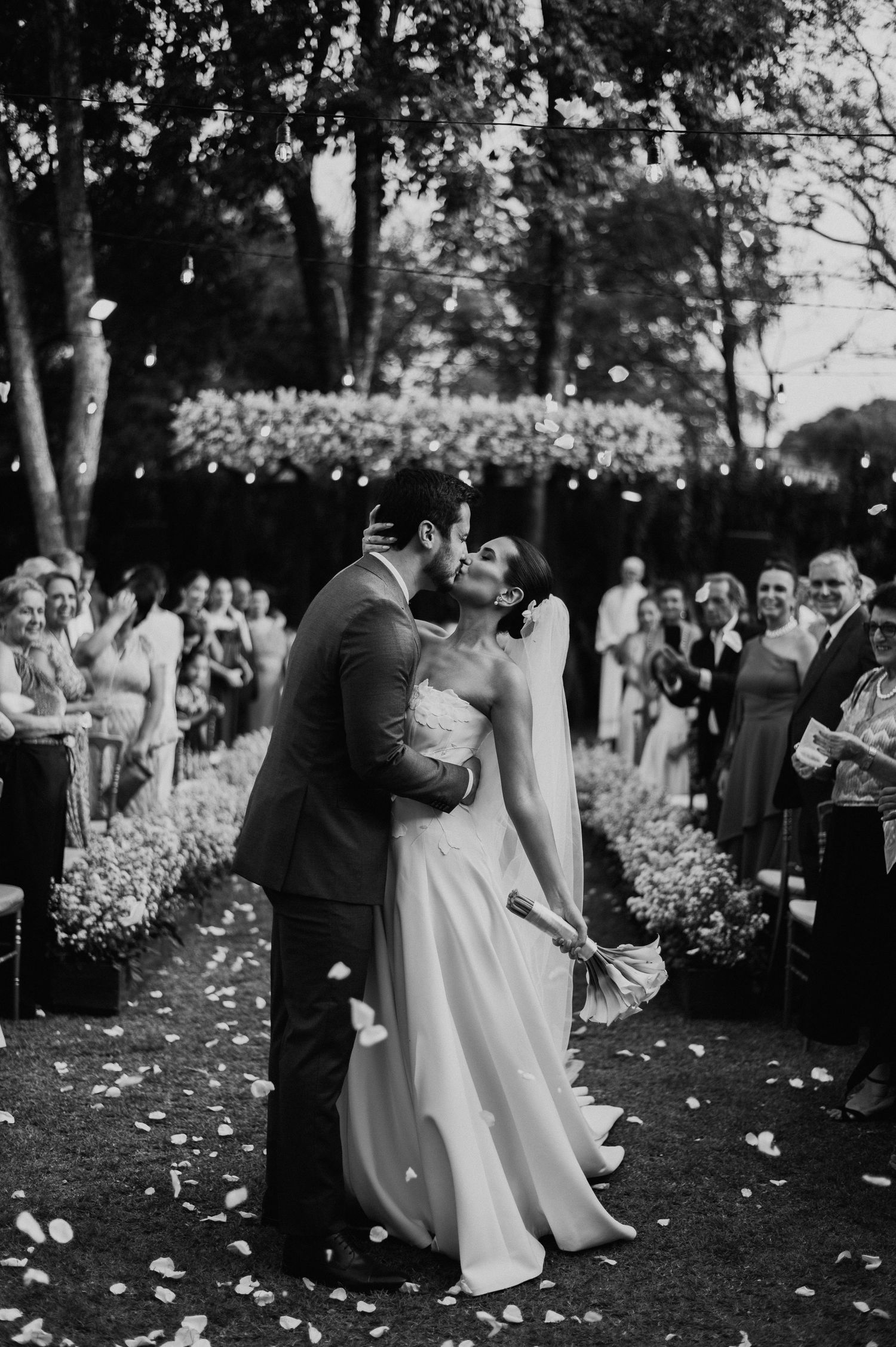 Romantic garden ceremony with guests looking on as couple shares intimate moment.
