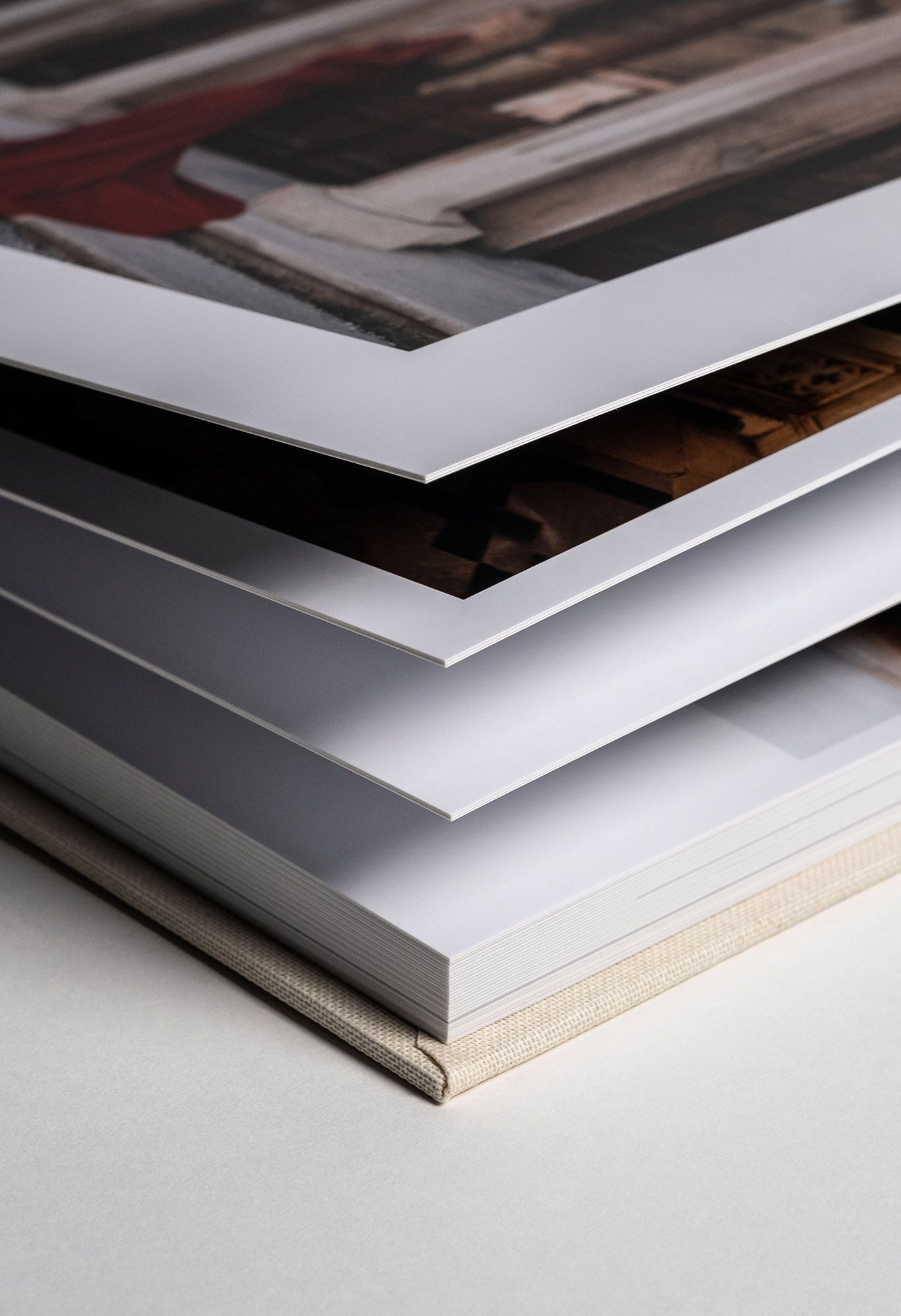 Stack of photo books with white edges showing layered pages at an angle against light background.