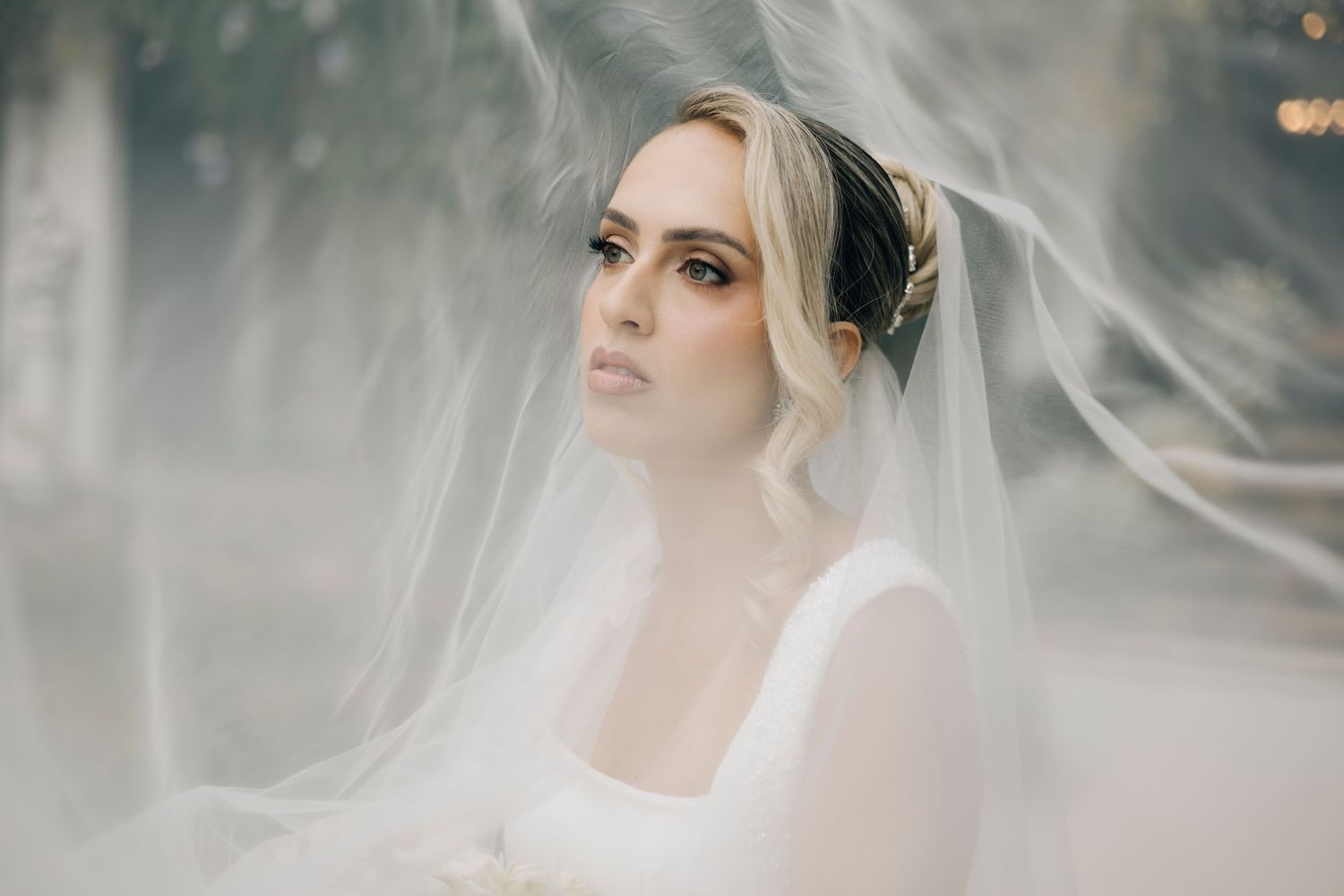An ethereal bridal portrait with flowing veil and soft light creating a dreamy, romantic atmosphere.