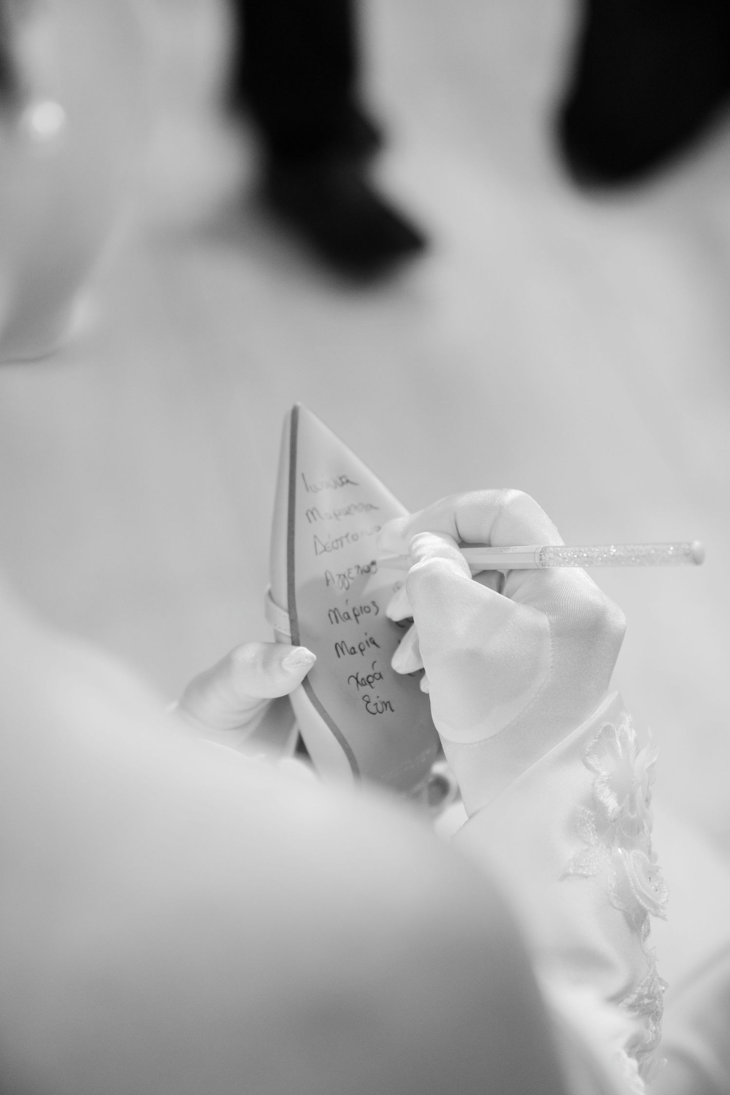Bride in white gloves writing names on wedding shoe sole, a cherished tradition.