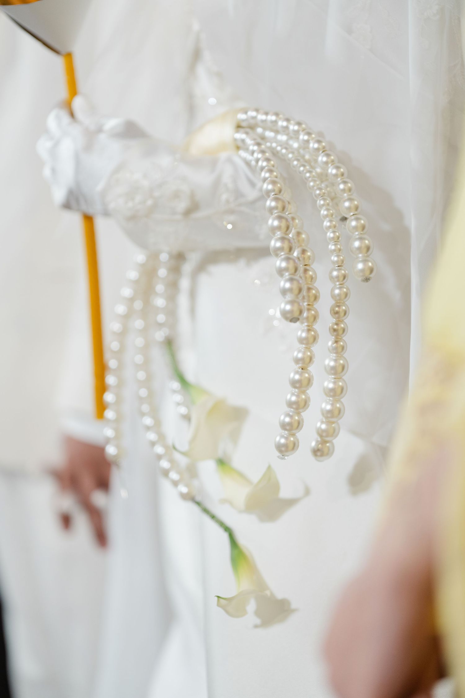 Bride holding elegant pearl cascade bouquet with white calla lilies on wedding day.
