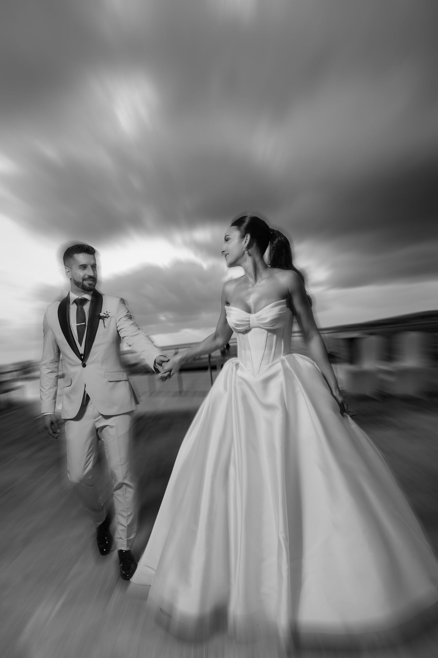 Bride and groom walk hand in hand smiling with dramatic blurred motion effect background.