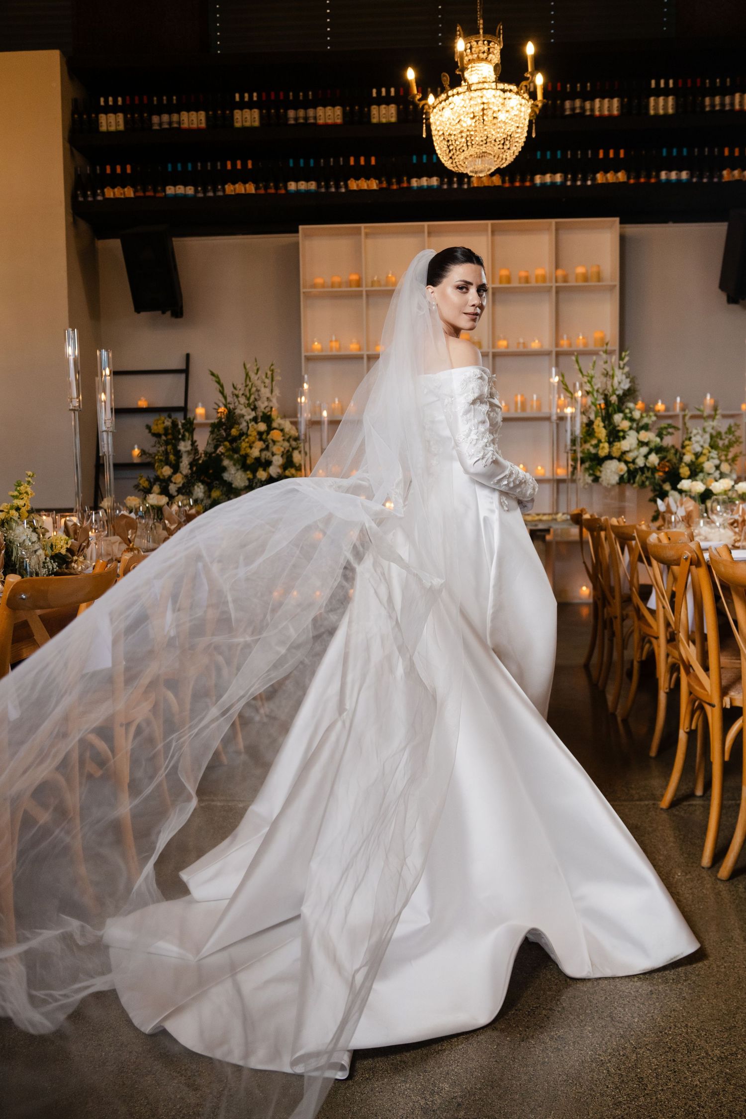 Bride twirling in a stunning white ball gown with flowing veil in a warmly lit wedding reception hall.