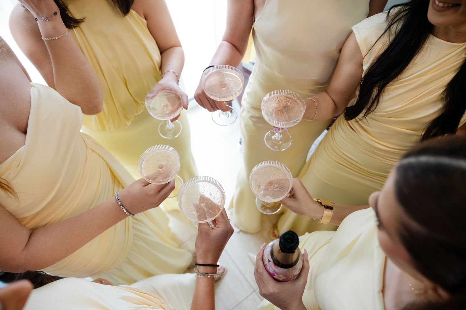 Bridesmaids in yellow dresses toasting with champagne glasses at a wedding celebration.