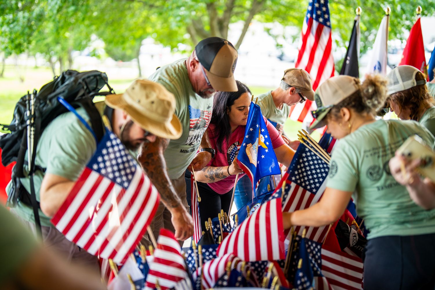 Group of people gathered at patriotic outdoor event with American flags and decorative elements.