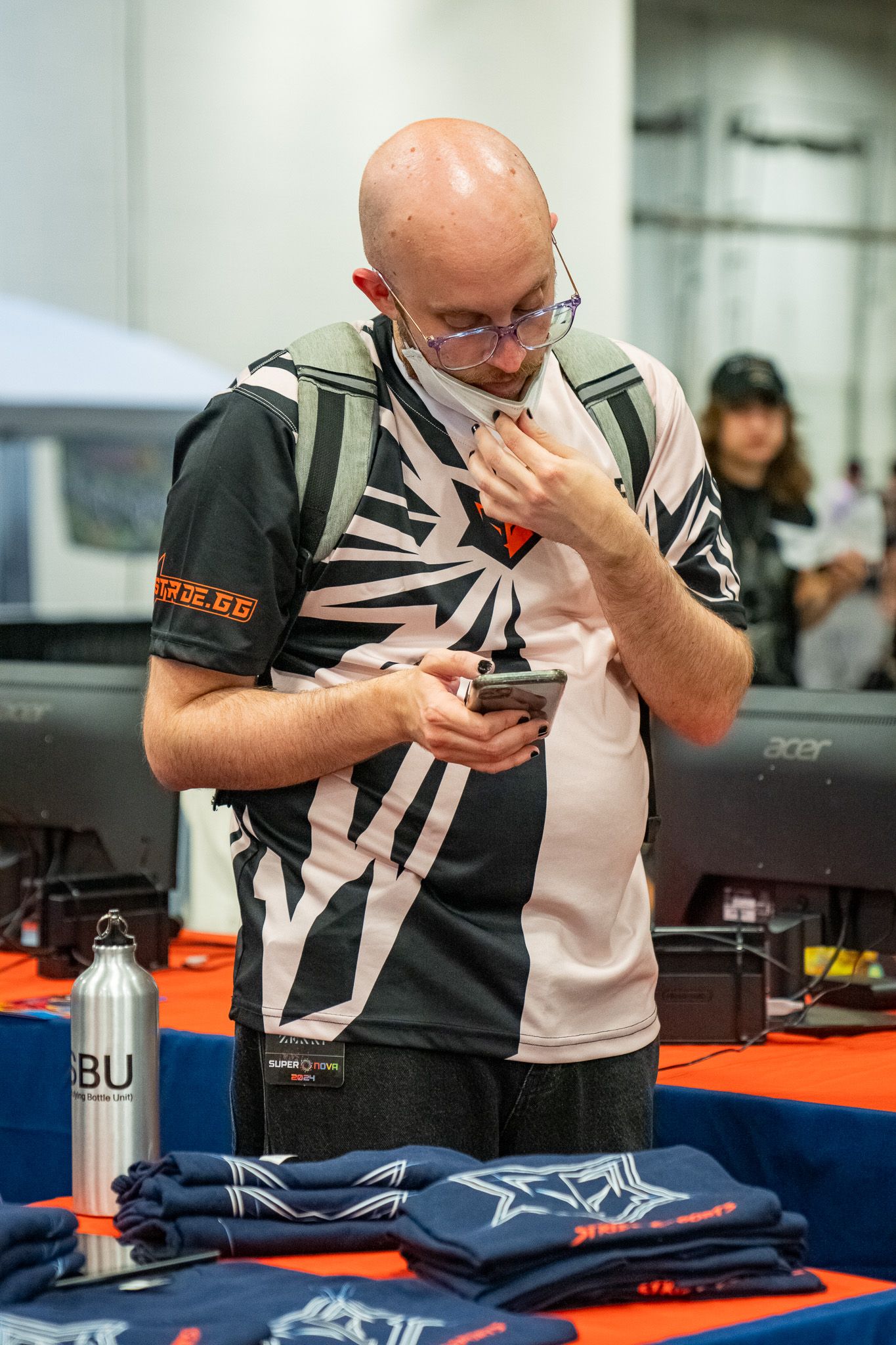 A focused participant bent over examining items on a blue table at what appears to be a competitive event.