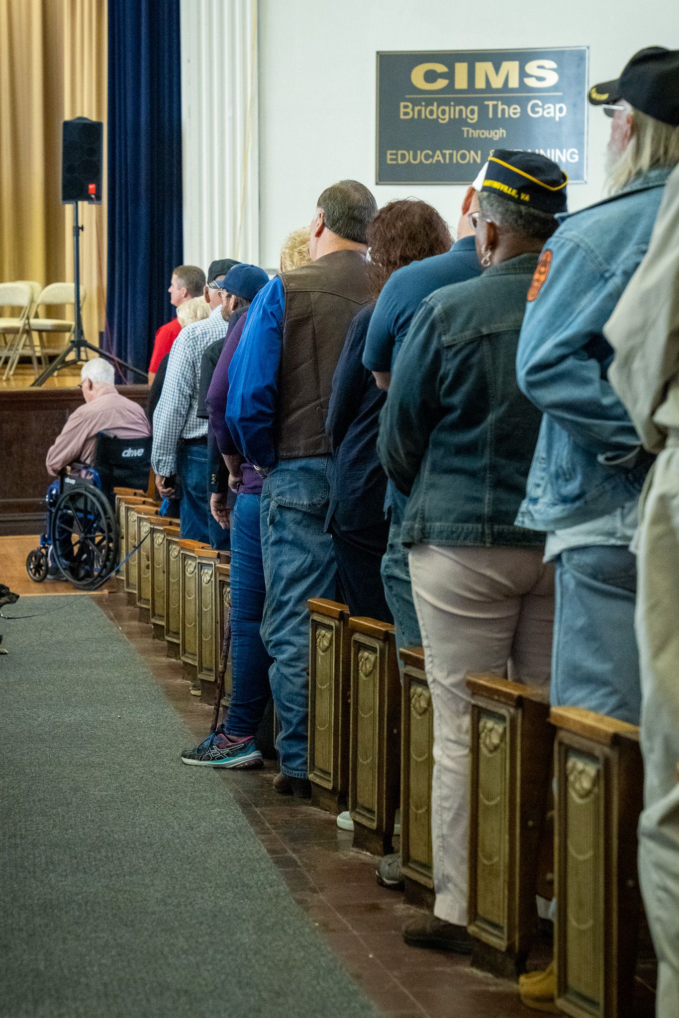 People standing in line at a CIMS education event, with wheelchair accessibility and military veteran presence visible.