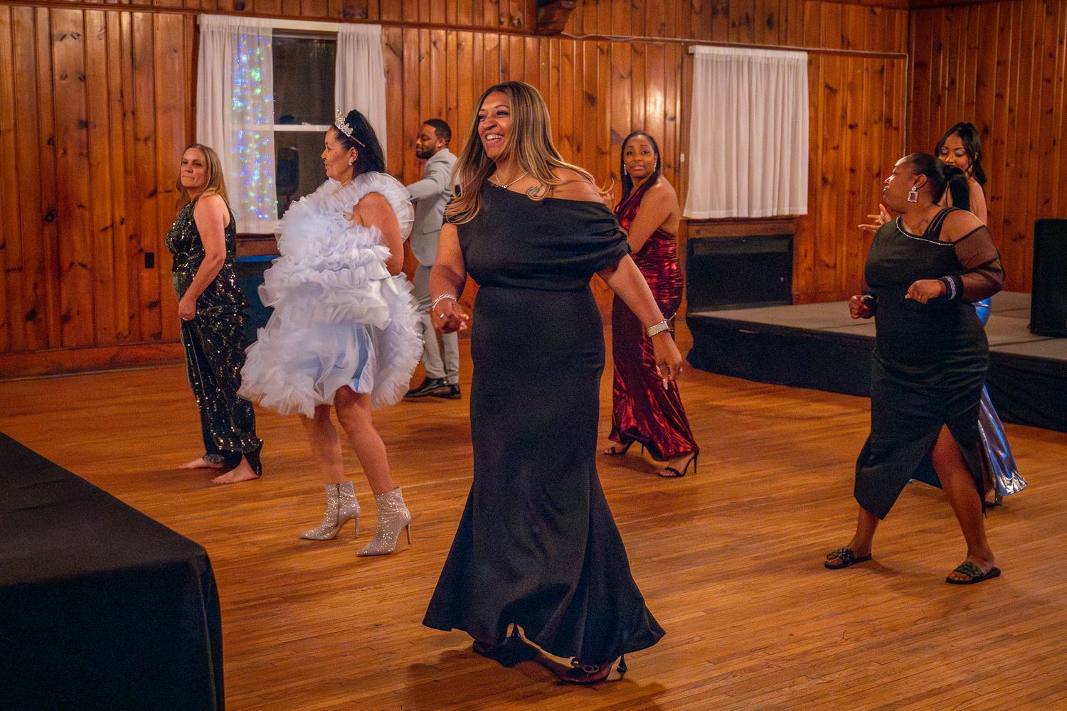 People dancing and enjoying themselves on a wooden dance floor at an indoor party or celebration event.