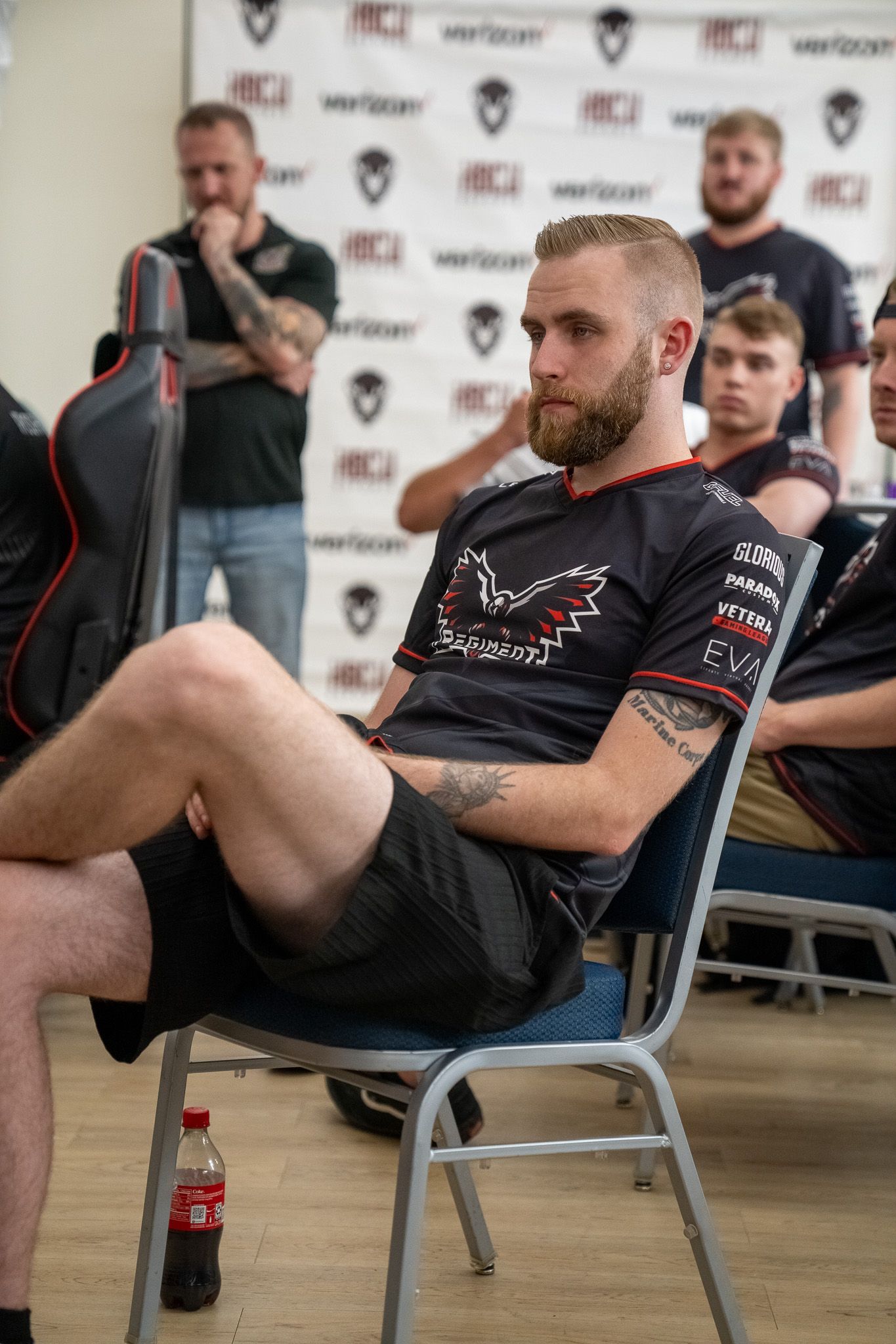 Person sits sideways in a chair at an event with Verizon sponsor banners visible in the background.