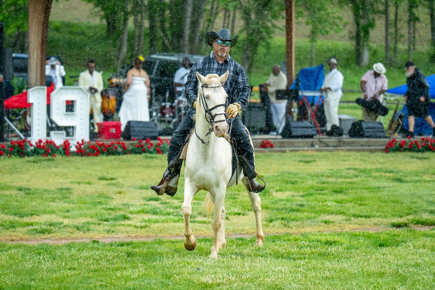 A person leads a white horse with a red blanket along a grassy field during an equestrian event.