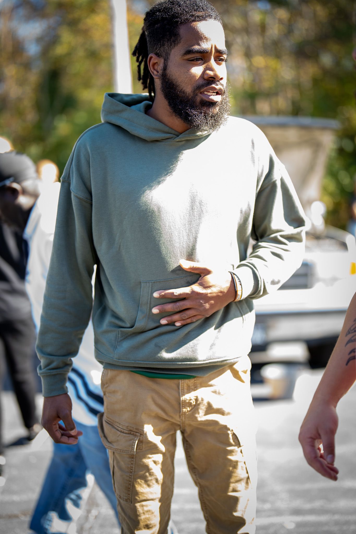 Person wearing a casual gray hoodie and khaki cargo pants walking outdoors on a sunny day.