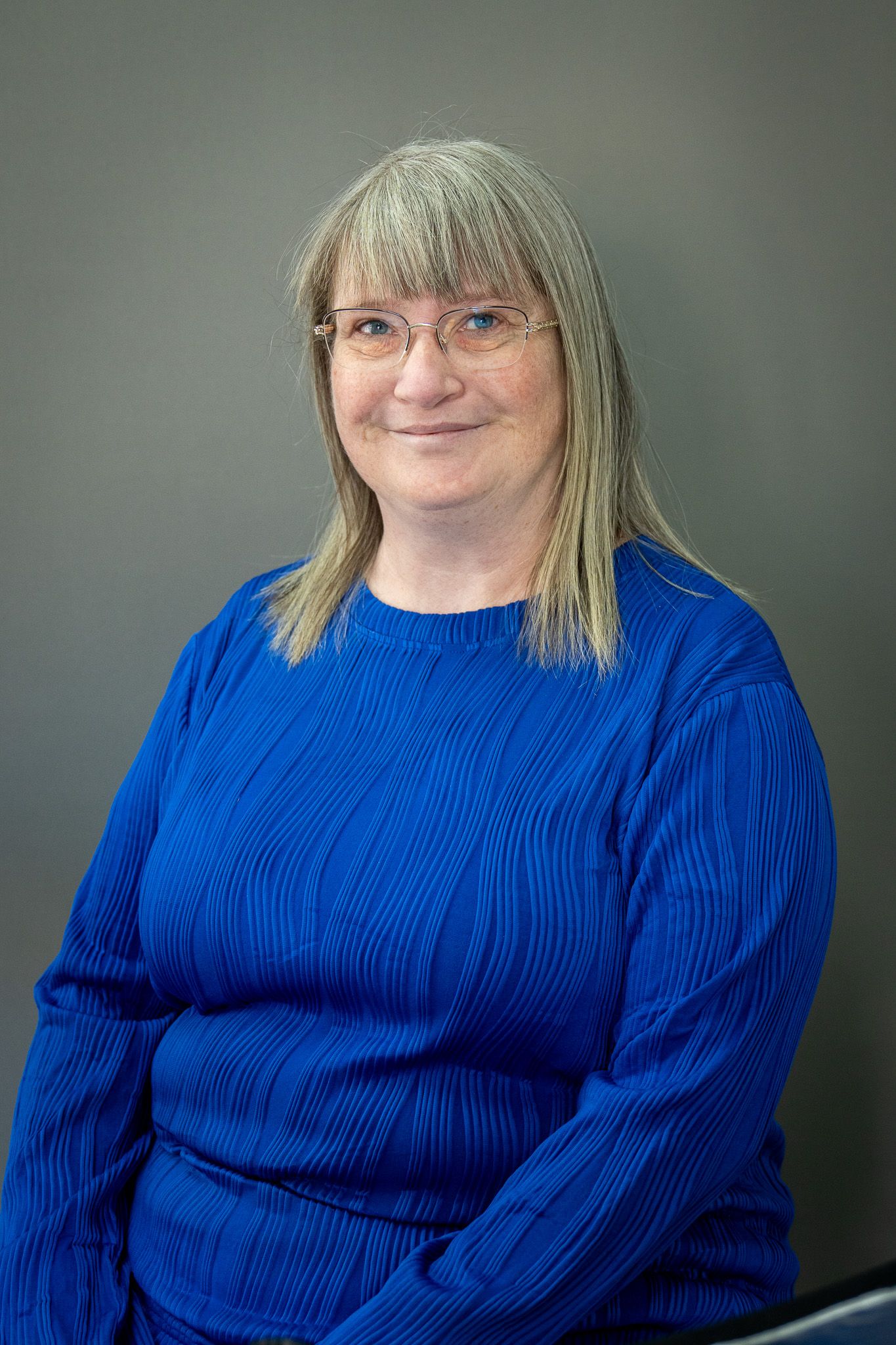 Sequence of photos showing someone in a vibrant blue sweater smiling against a gray background.