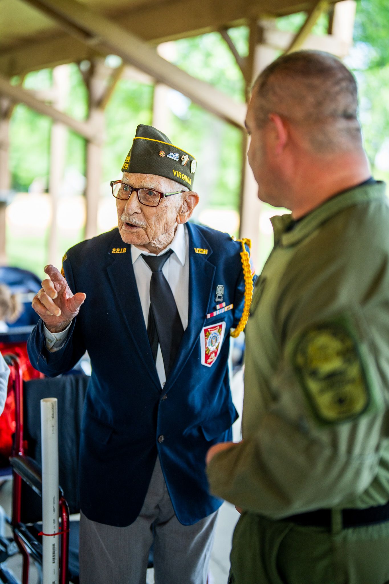 Veterans in military uniforms having an animated conversation at an outdoor event.