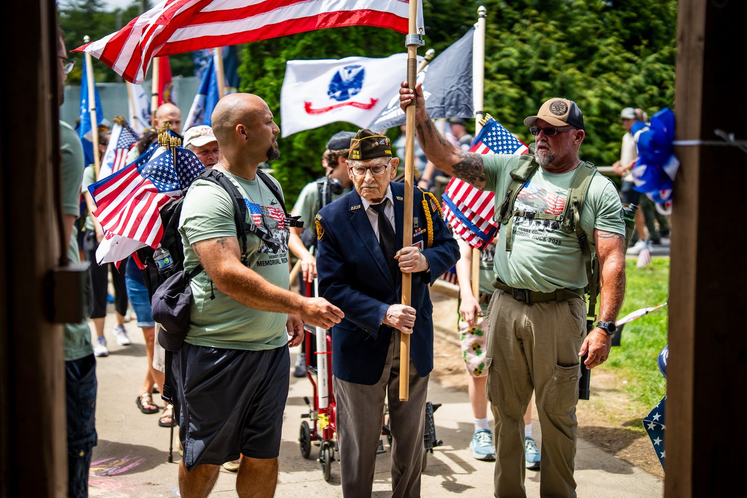 Group gathers outside for Memorial Day celebration with American flags and patriotic decorations visible.