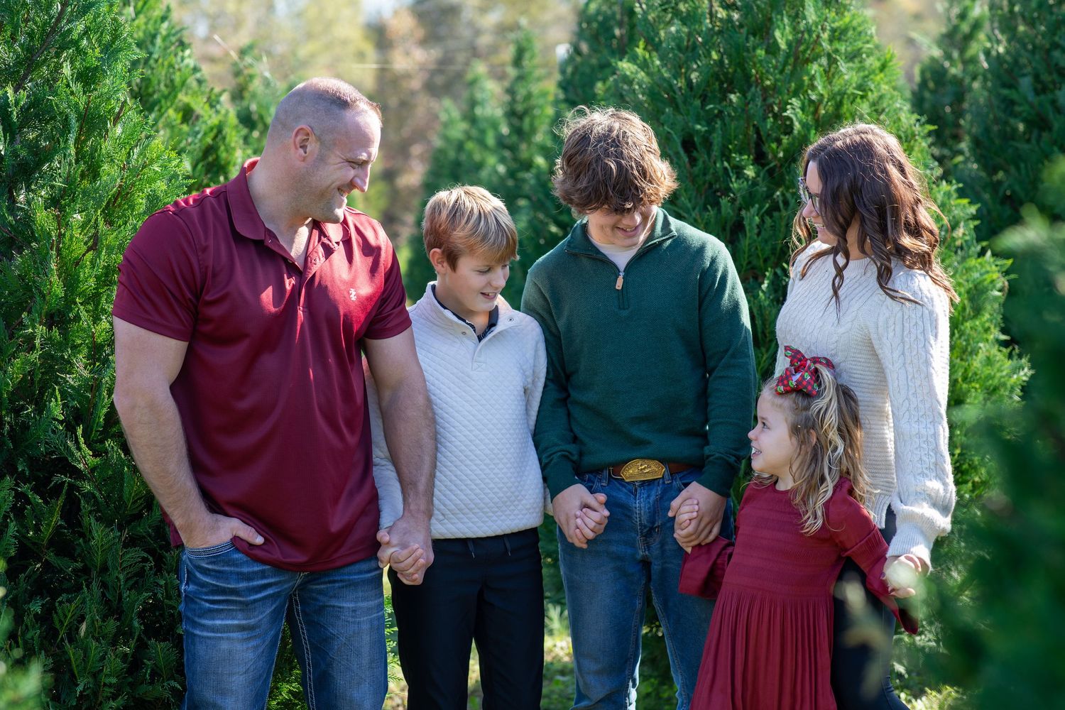 Family of five dressed in coordinated holiday outfits, standing together between Christmas trees — Christmas mini session in York County, SC