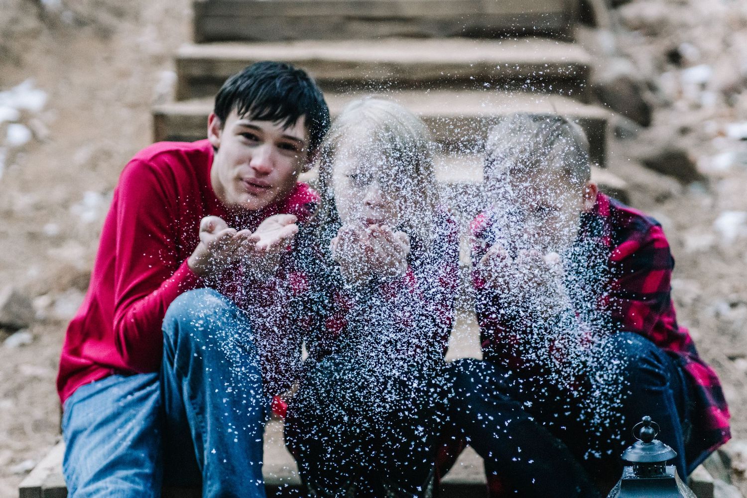 Snow falling around person sitting on stone steps during winter photo shoot.