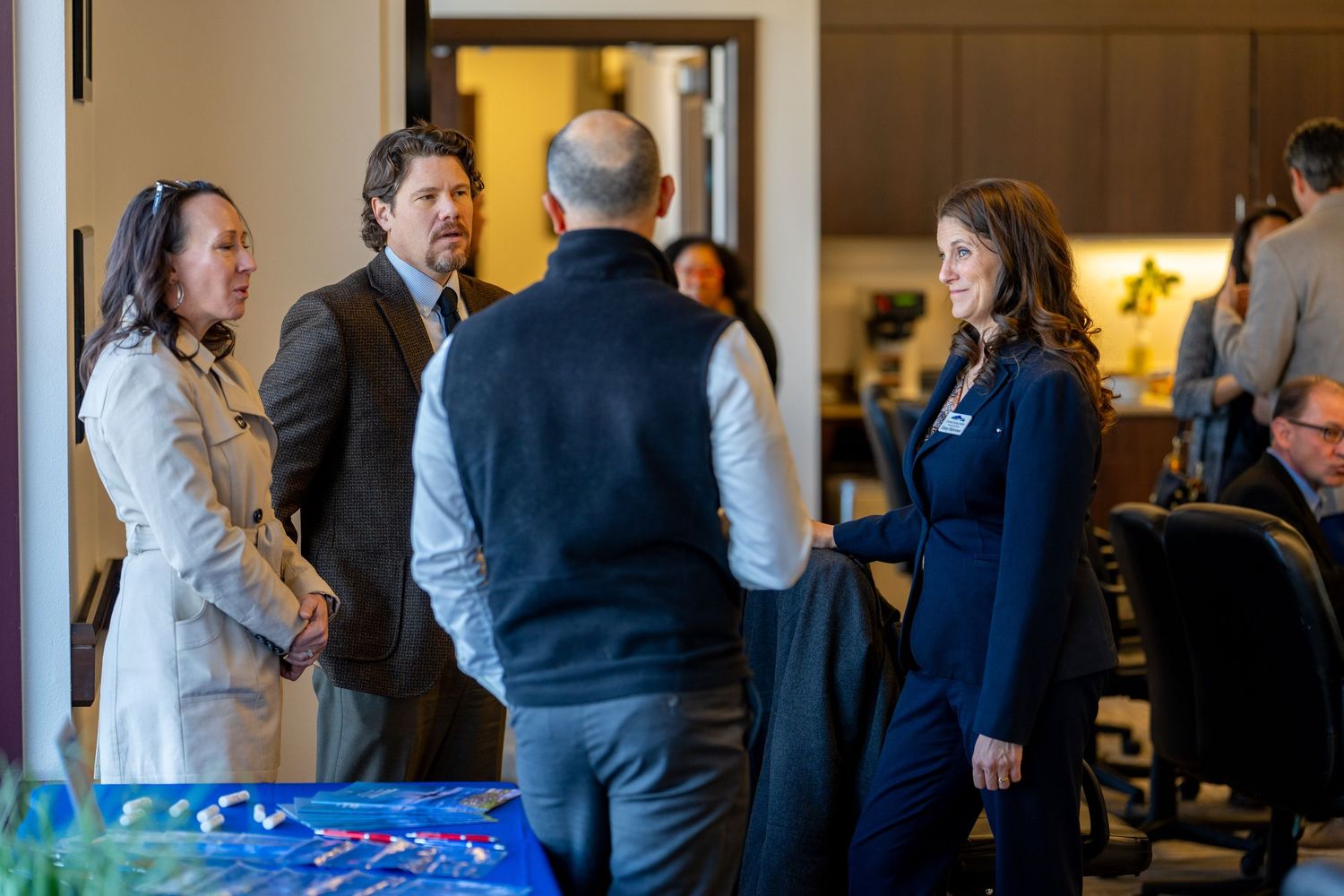 Professionals networking and shaking hands at a corporate event in a modern office setting.