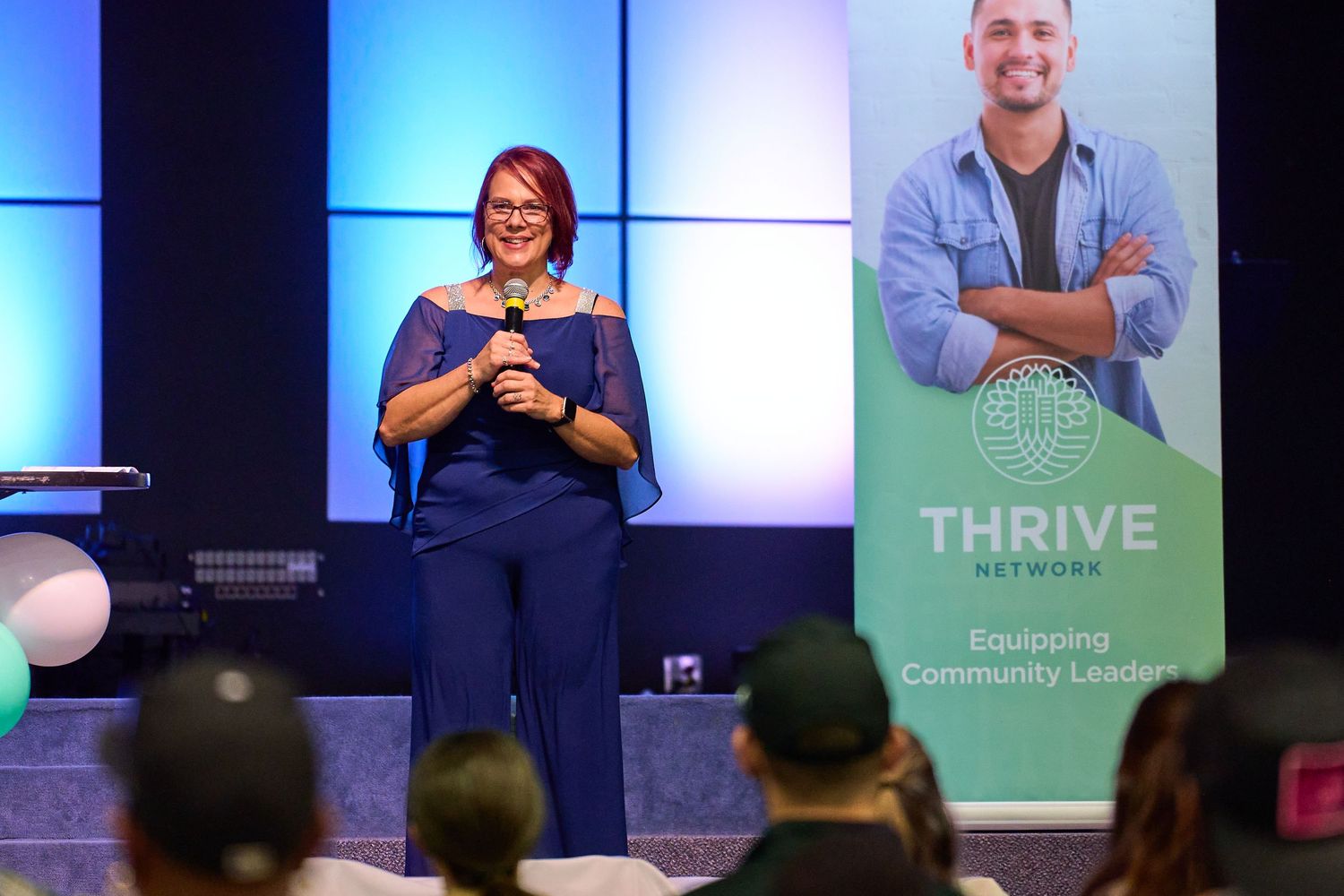 Speakers present on stage at a business conference with blue lighting and Thrive branding in the background.