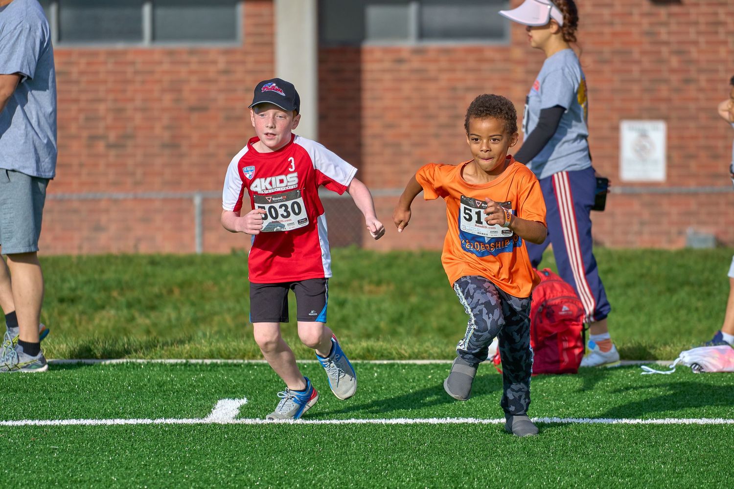 Young athletes sprint across a sports field during a youth competition event.