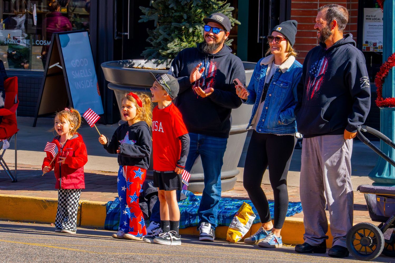Children in colorful costumes walk down a sidewalk during a Halloween trick-or-treat event at a shopping center.