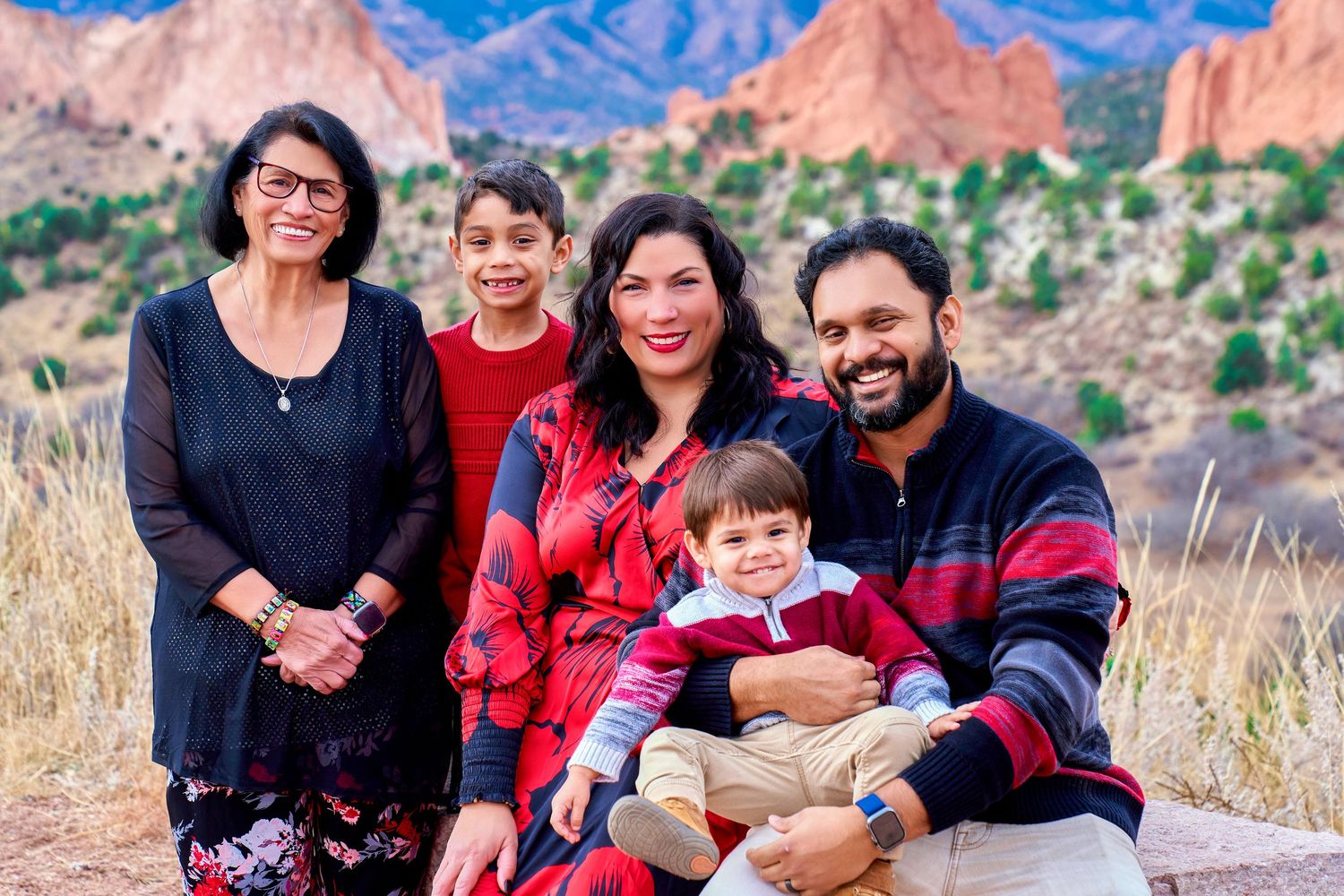 Happy family of five posing together against red rock mountains in Colorado.