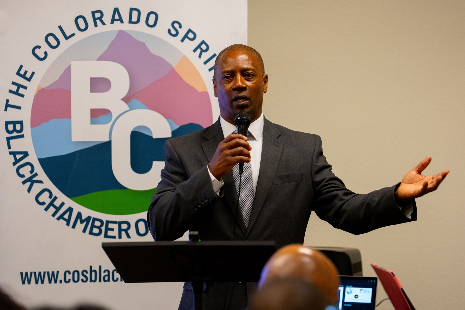 A speaker gestures while giving a presentation at the Colorado Springs Chamber of Commerce event.