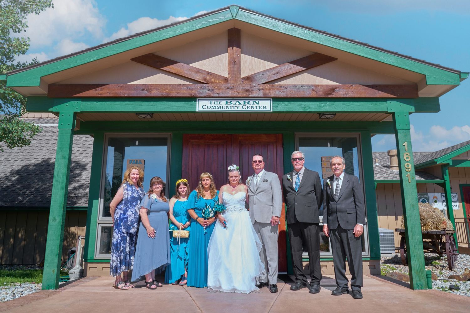 Wedding party group photo at a rustic green gazebo.